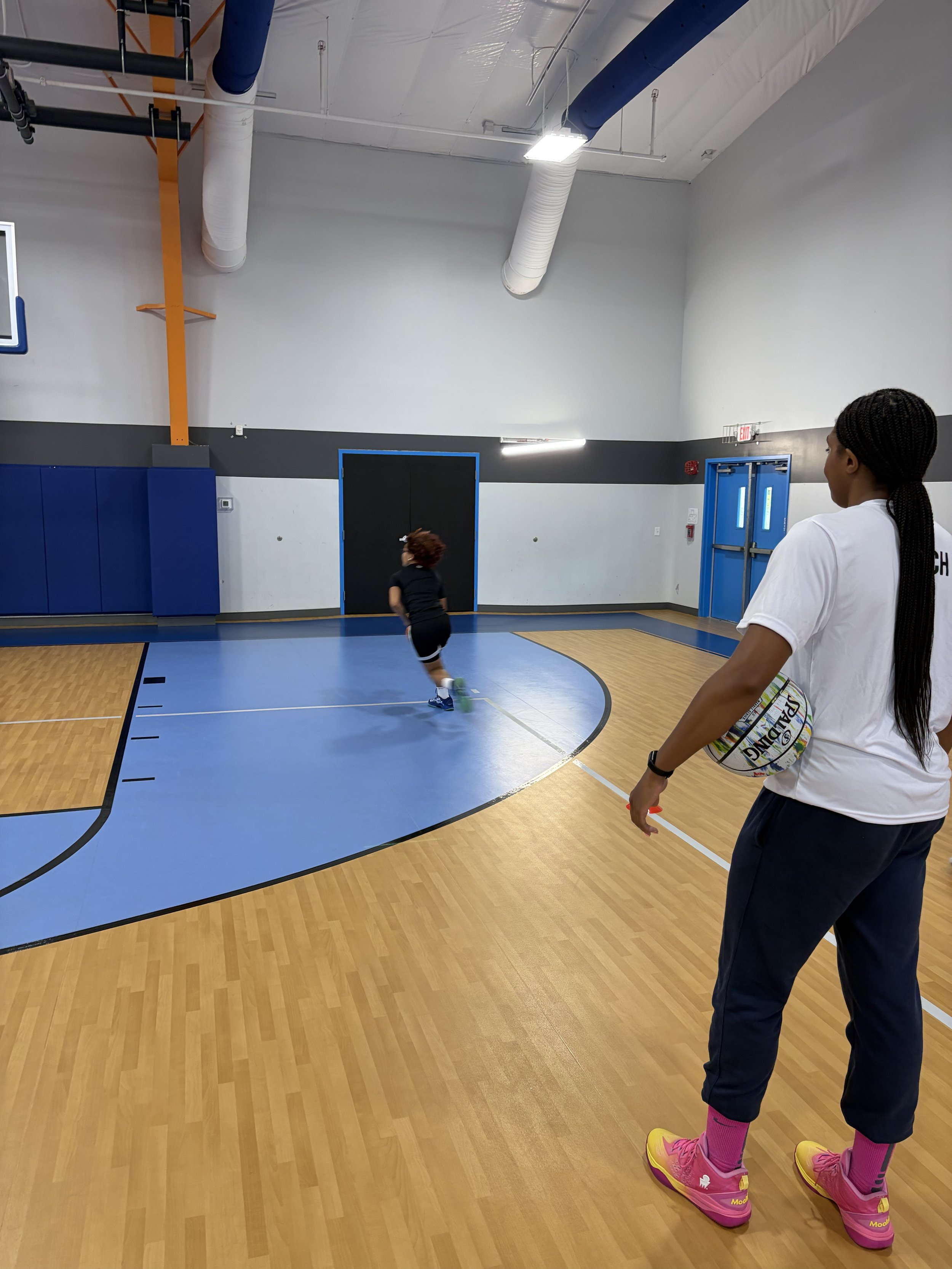 Maya Dodson coaches a young basketball player during a training session