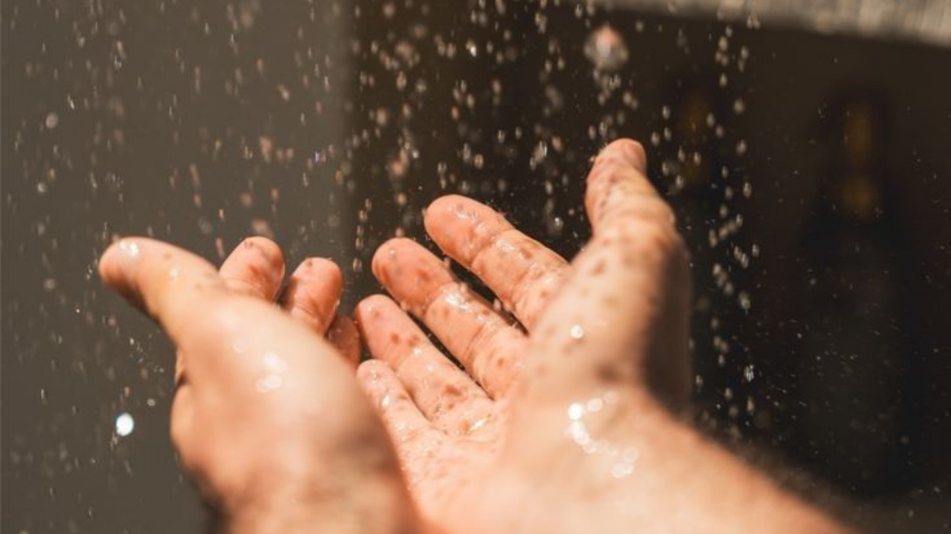 A person washing their hands with water splashing.