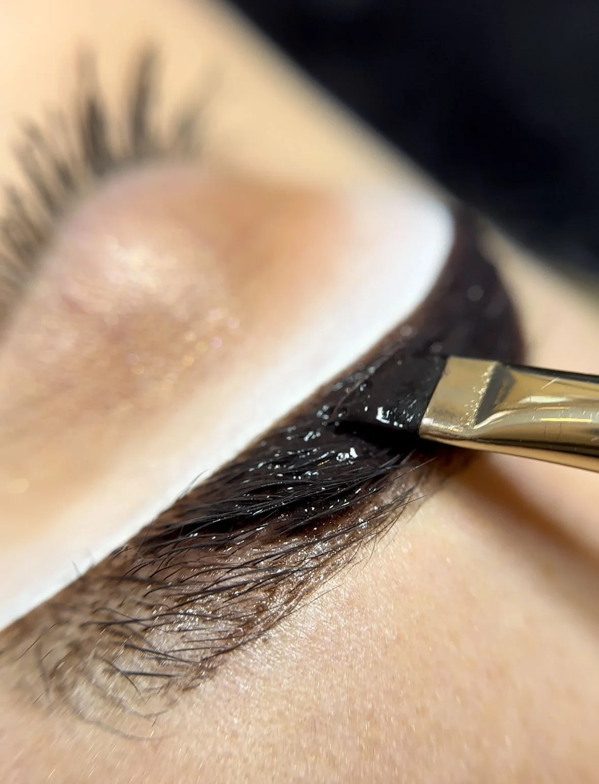 Close-up of a person applying eyelash extensions with a small brush
