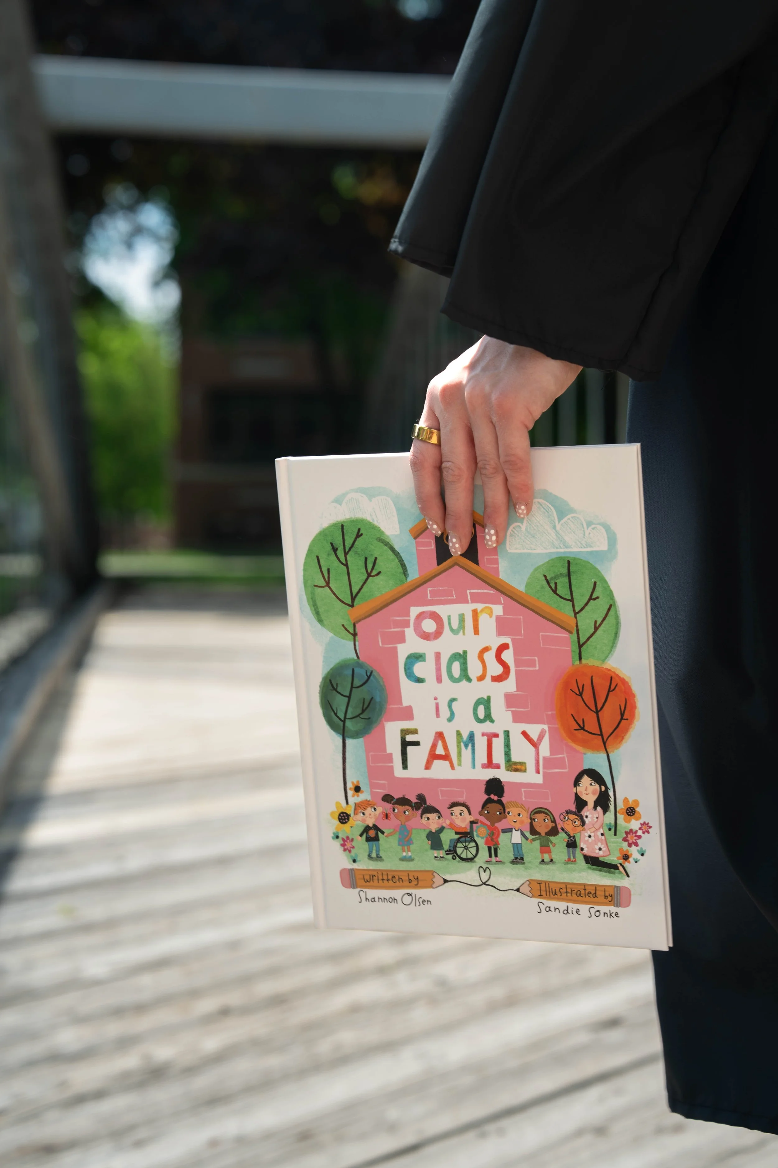 Person holding the children's picture book “Our Class Is a Family” by Shannon Olsen.