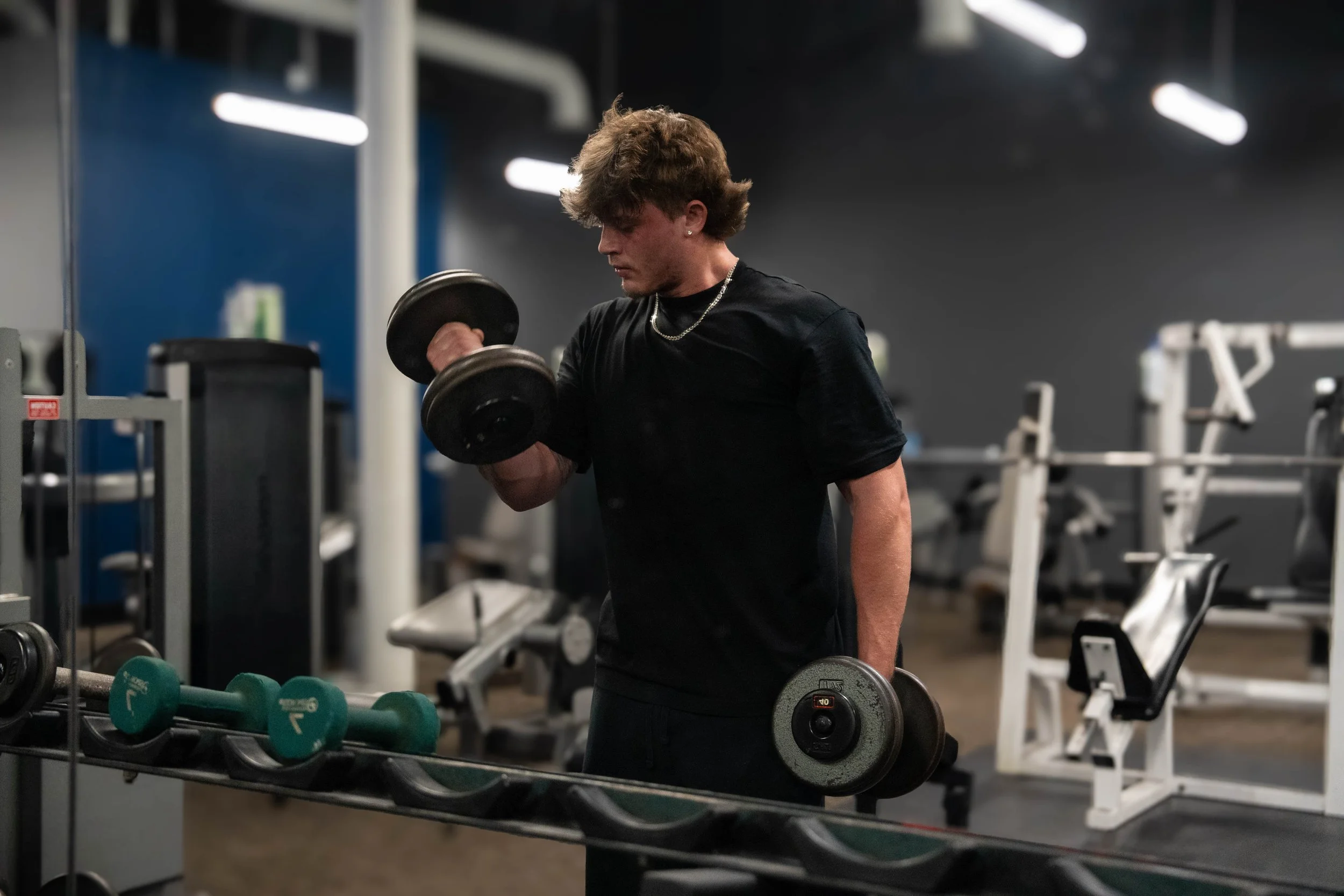 Man performing dumbbell curls in a gym