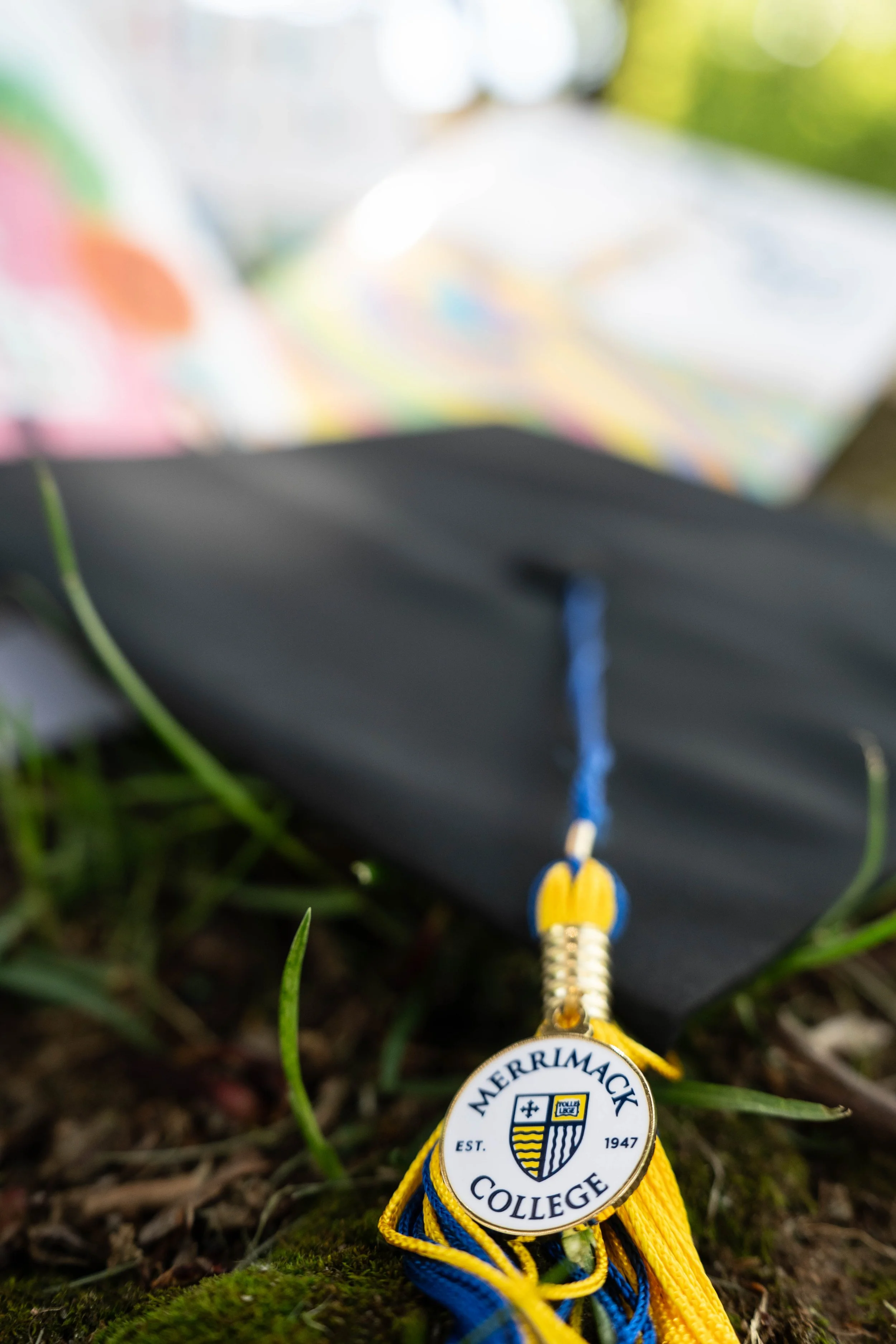 Mercyhurst College graduation medal with blue and gold tassel lying on moss
