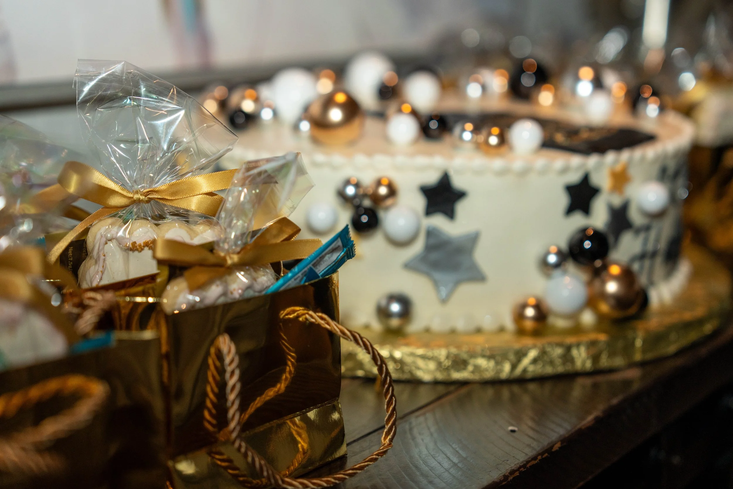 Gold-wrapped holiday gift basket with treats beside festive black, white, and gold decorations
