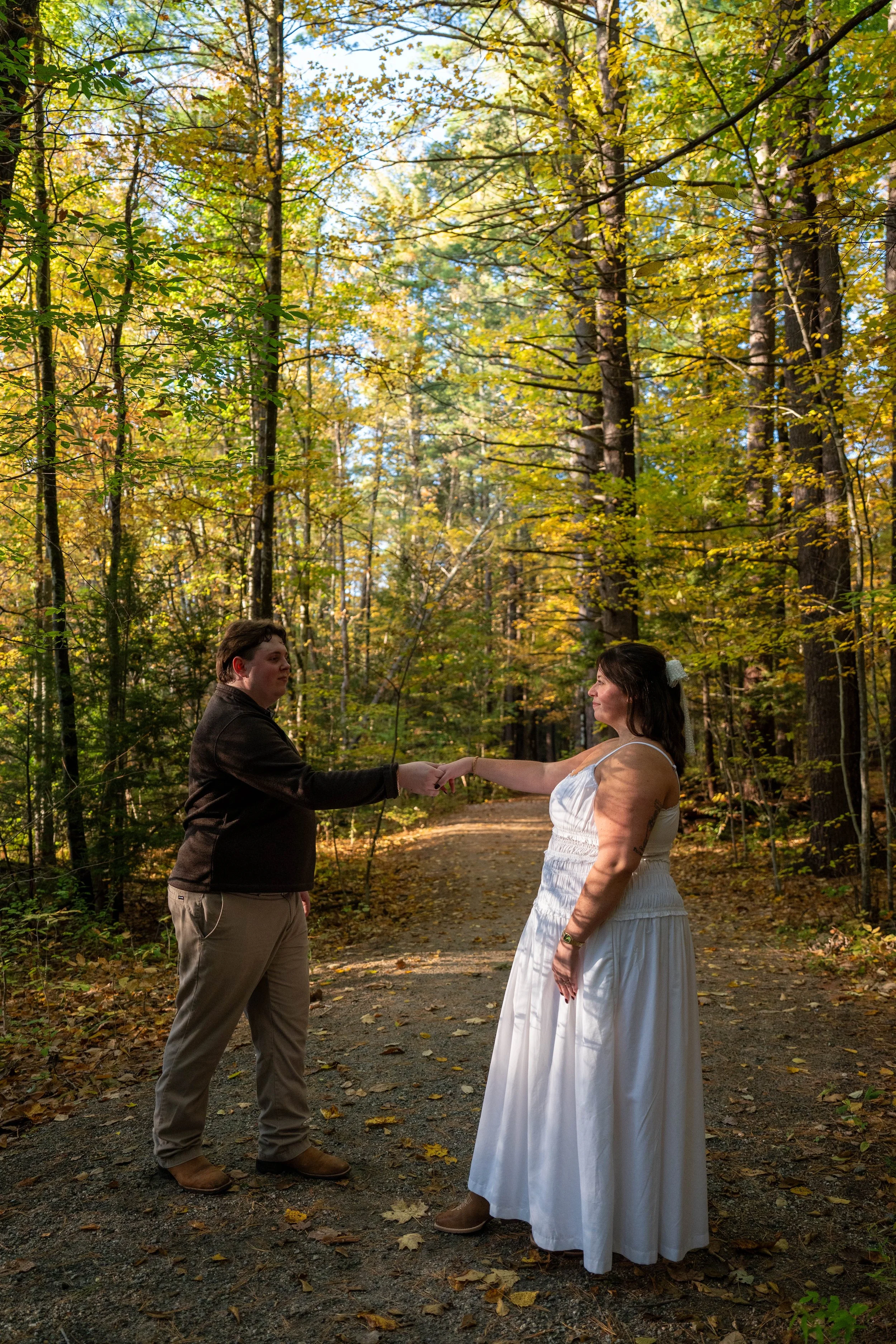 Couple holding hands on a forest trail during an autumn wedding photo session