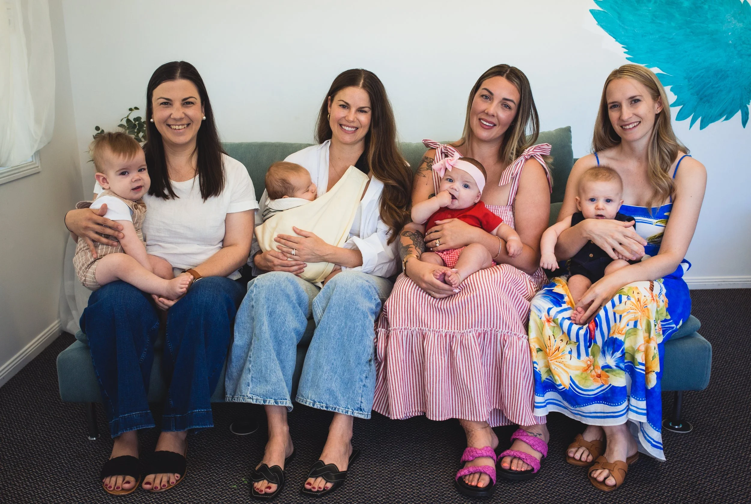 A groups of mums holding up theirs babies for a group photo, all smiling and having a great time