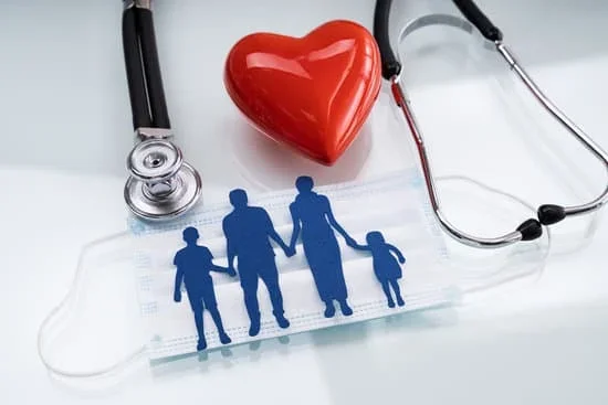 Stethoscope draped around a paper cut‑out family with a red heart on a blue medical mask.
