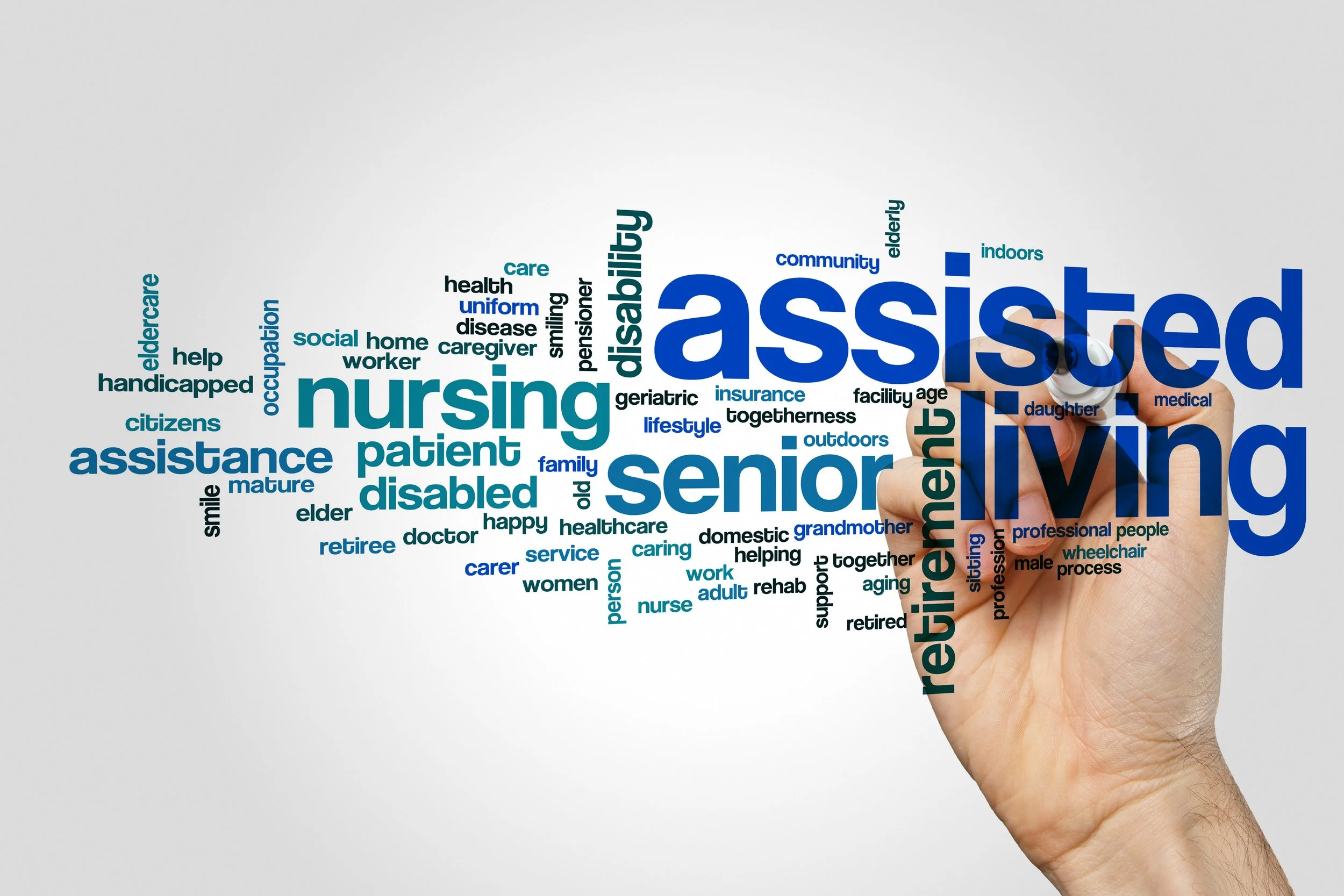 A hand writing on a transparent surface with a black marker, creating a word cloud related to assisted living for seniors, including terms like 'nursing,' 'senior,' 'living,' 'assisted,' and 'retirement'.