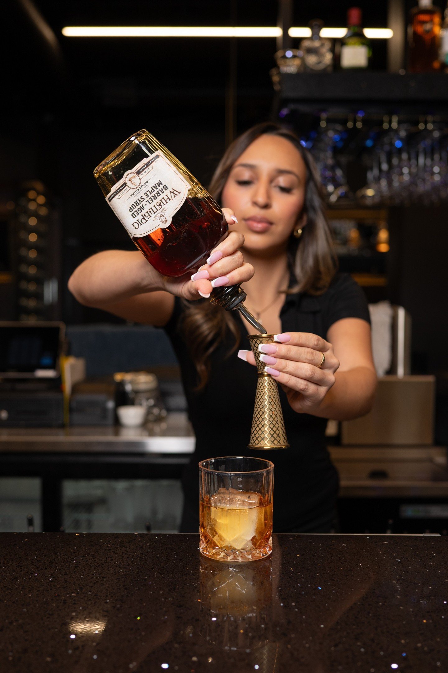 "It starts before the first sip.

A bottle tilted with precision.
Amber measured into gold.
A single, clear cube waiting.

Citrus oils released over the surface.
Bitters folded in.
Time slowing down as it settles.

Then, the lift of the glass.
T