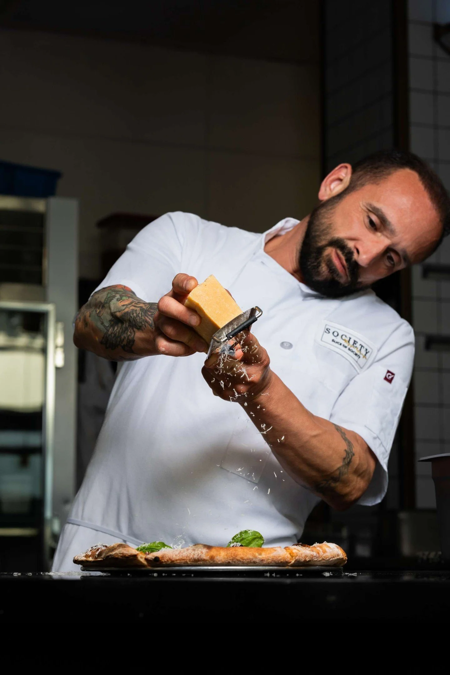 "It doesn&rsquo;t begin with the slice.

It begins in the air.

Cheese falling in soft ribbons.
Basil released by hand, not scattered, but placed.
Heat rising, crust lifting, edges blistering just enough.

Seventy-two hours of fermentation behin