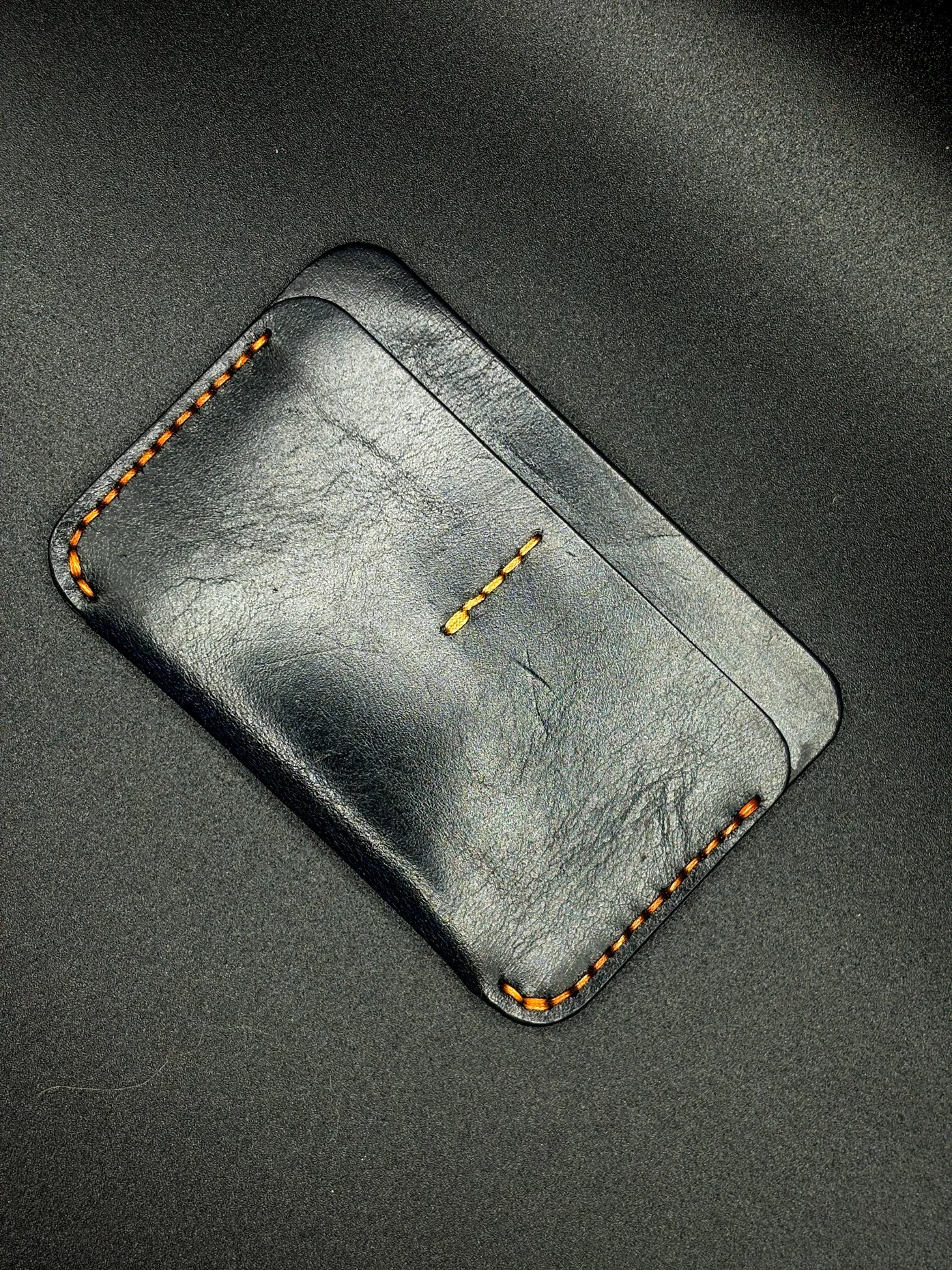 a small black leather wallet with red seam by chen creative studio