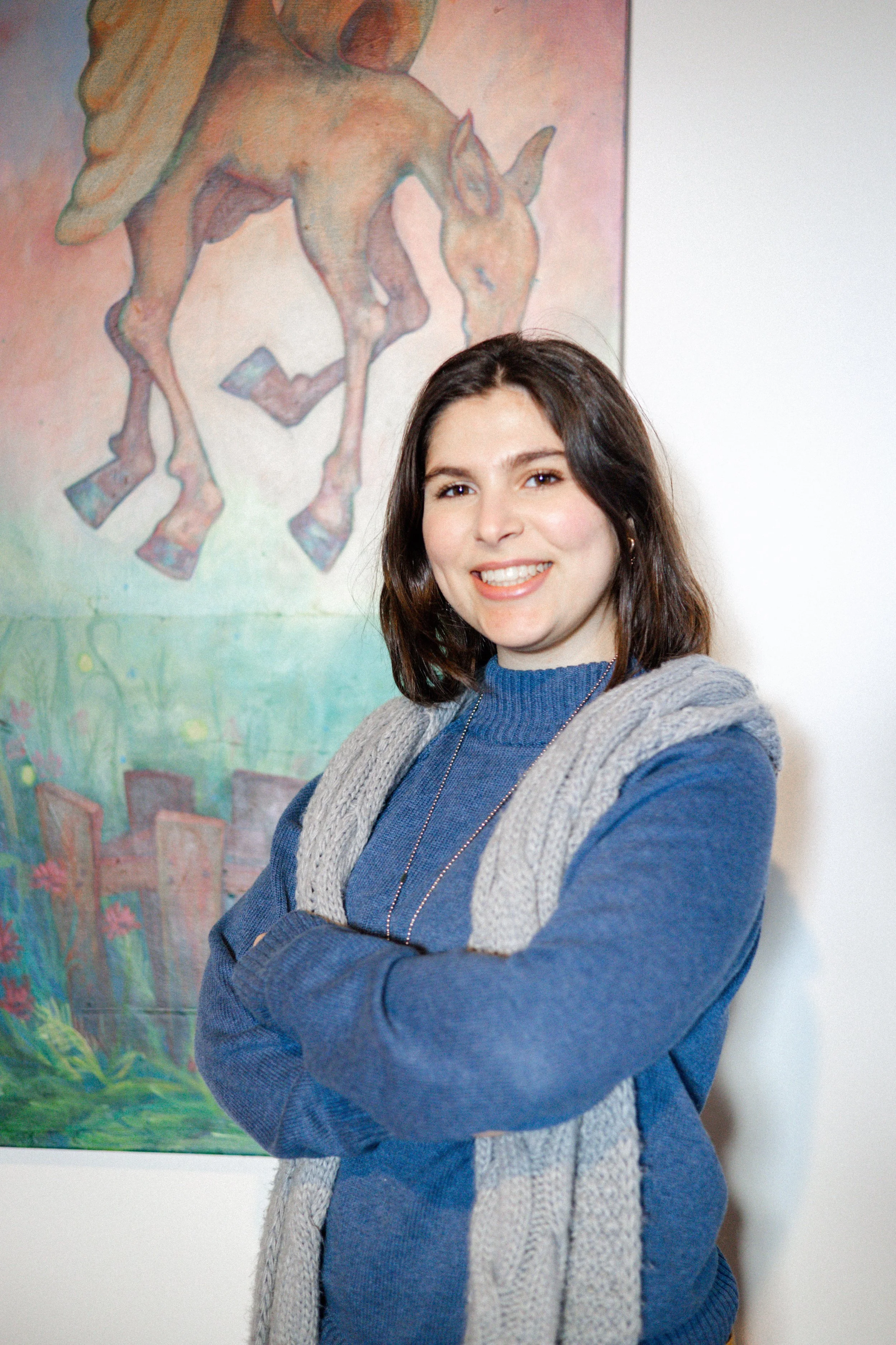 shaza umran standing next to her large acrylic painting at her solo exhibition sky roots sponsored by third pine collective