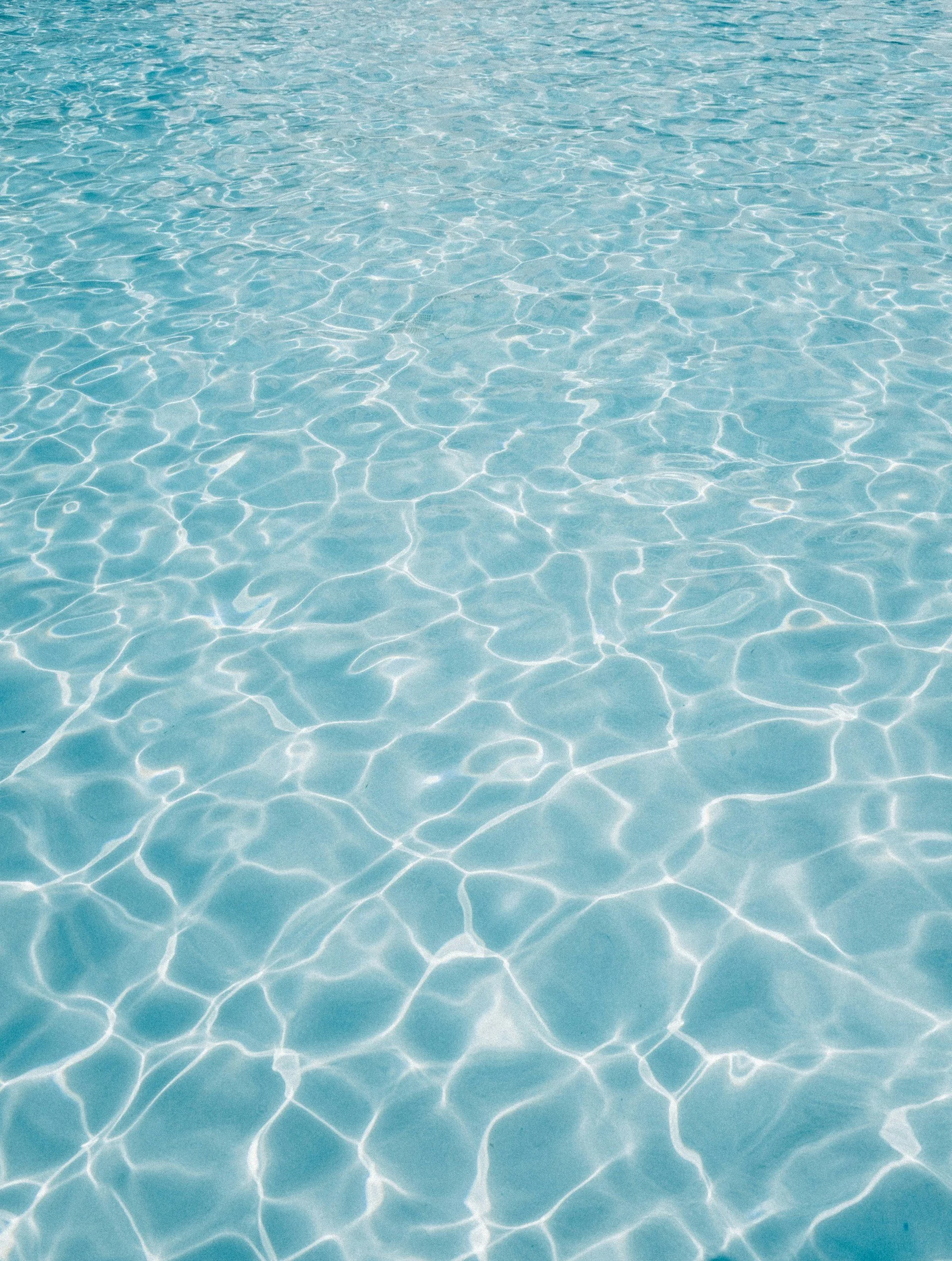 Clear blue swimming pool water with sunlight reflections.