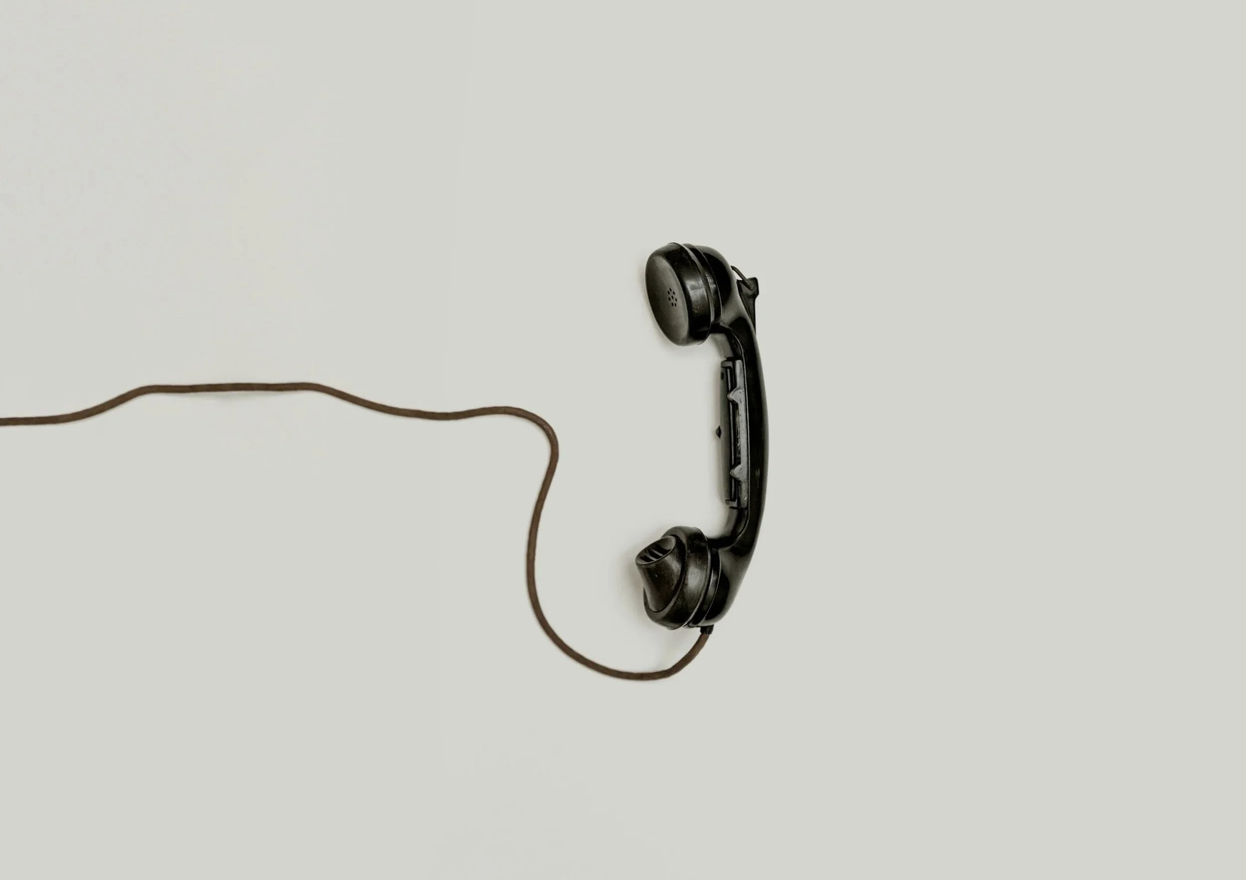 Black vintage telephone with cord on plain white background.