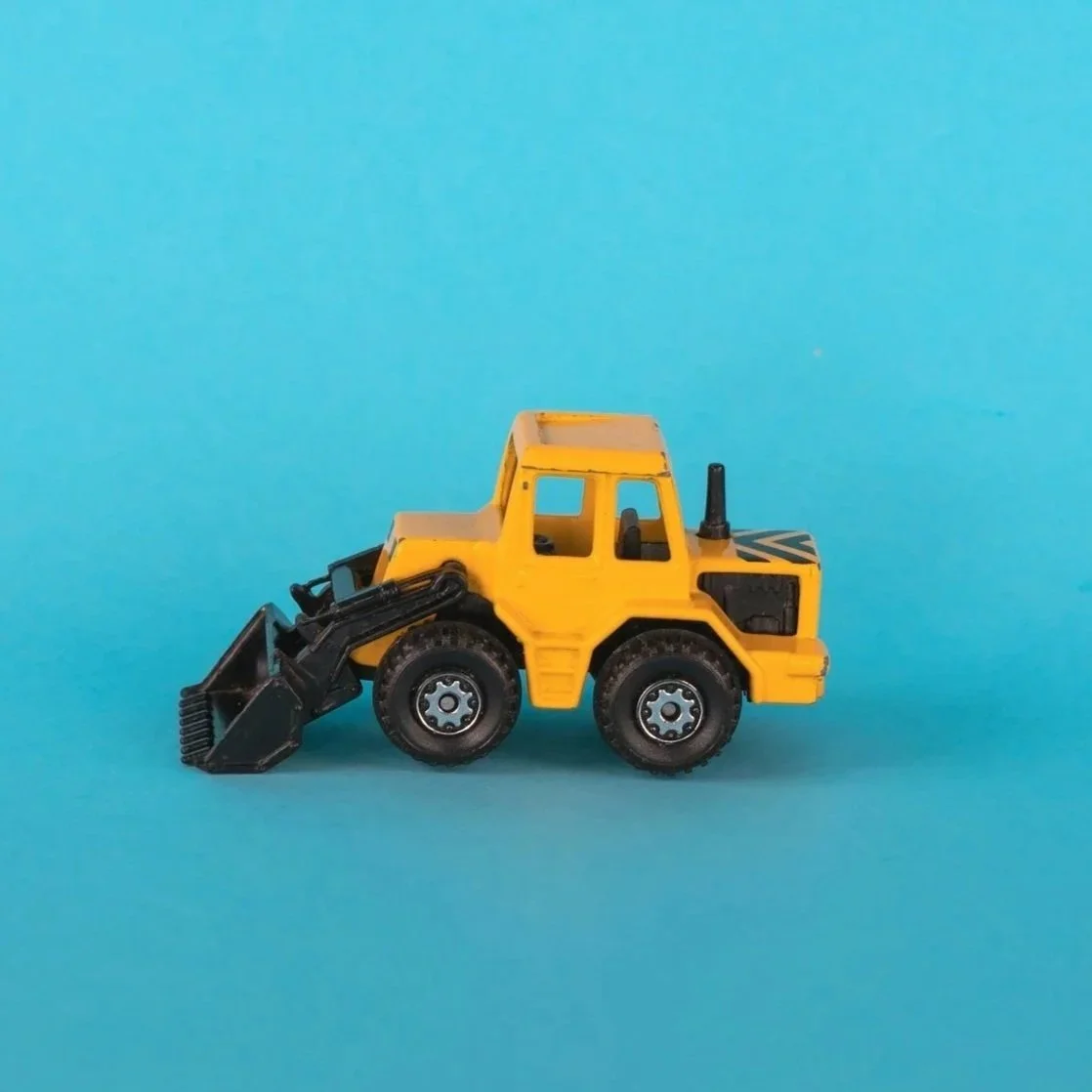 Small yellow toy construction loader on blue background.