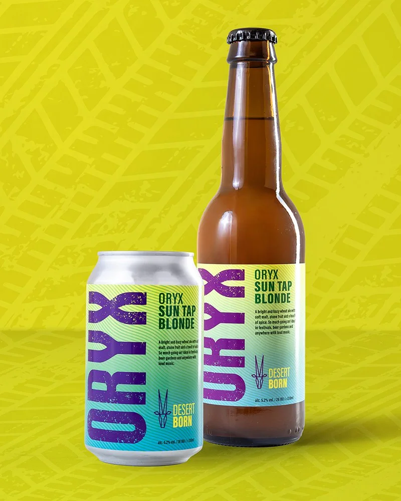 Can and brown beer bottle labeled "Oryx Sun Tap Blonde" with a yellow and purple design, placed against a bright yellow background with leaf patterns.