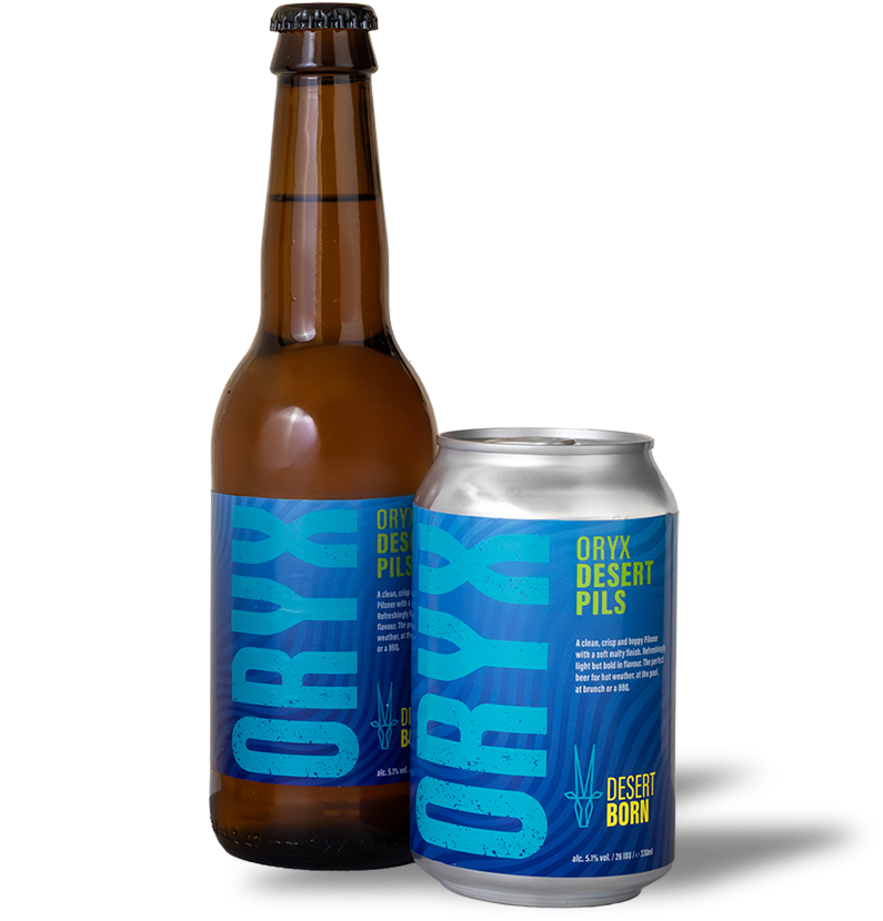 A brown glass bottle and a silver can of Oryx Desert Pils beer with blue labels, featuring the text 'Oryx Desert Pils' and 'Desert Born'
