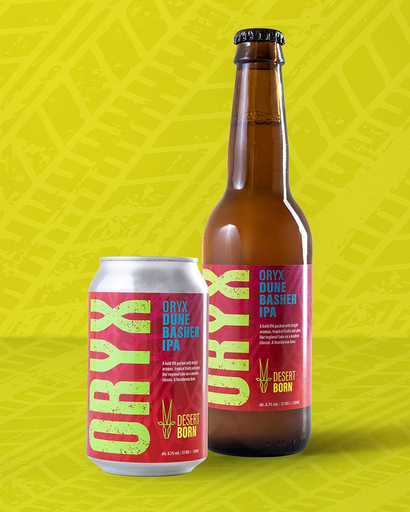 A bottle and a can of Oury Dune Basher IPA beer with colorful labels, placed on a yellow background with leaf patterns.