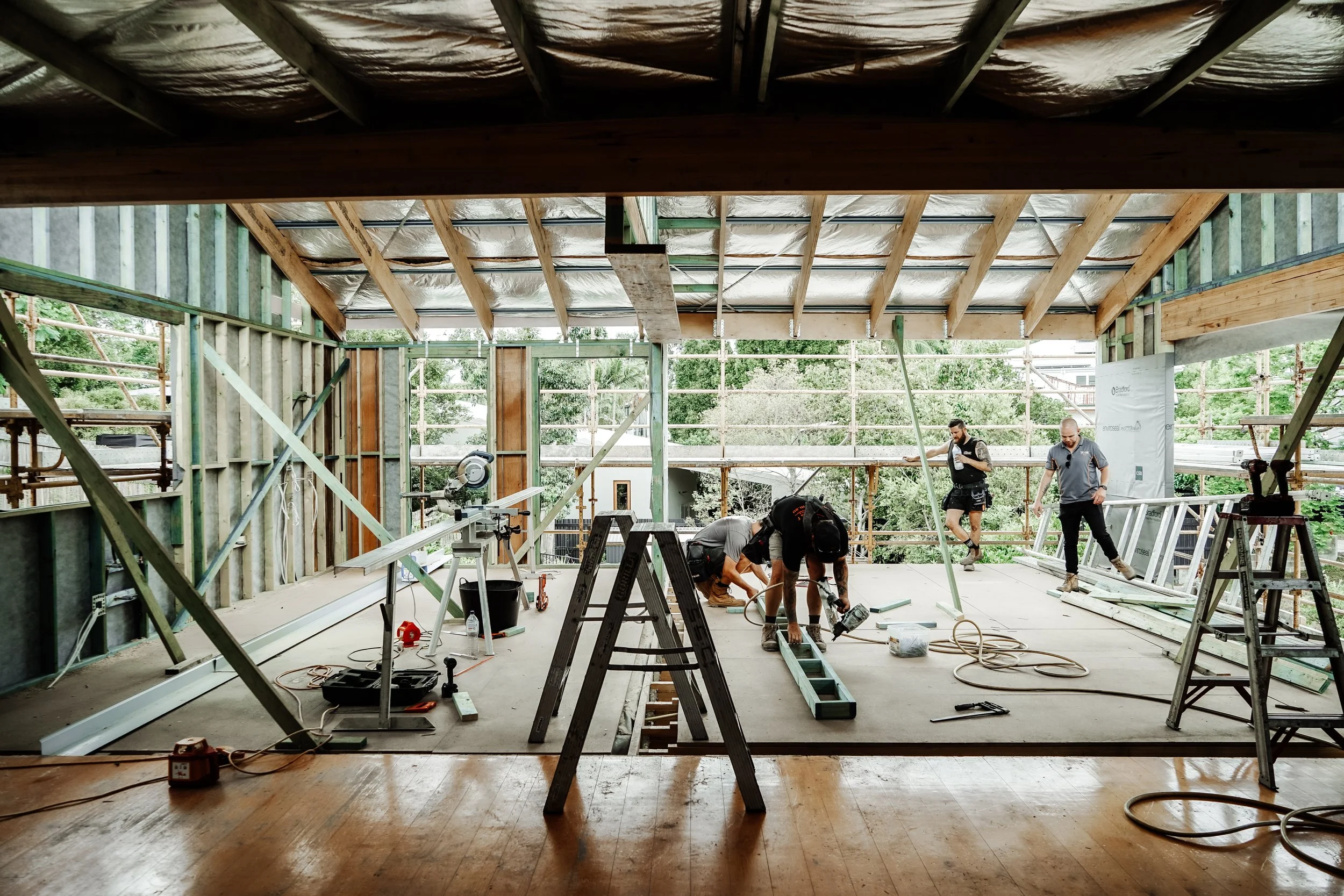 Builders working on a residential renovation in Red Hill, Brisbane, with exposed timber framing and structural renovation work underway.
