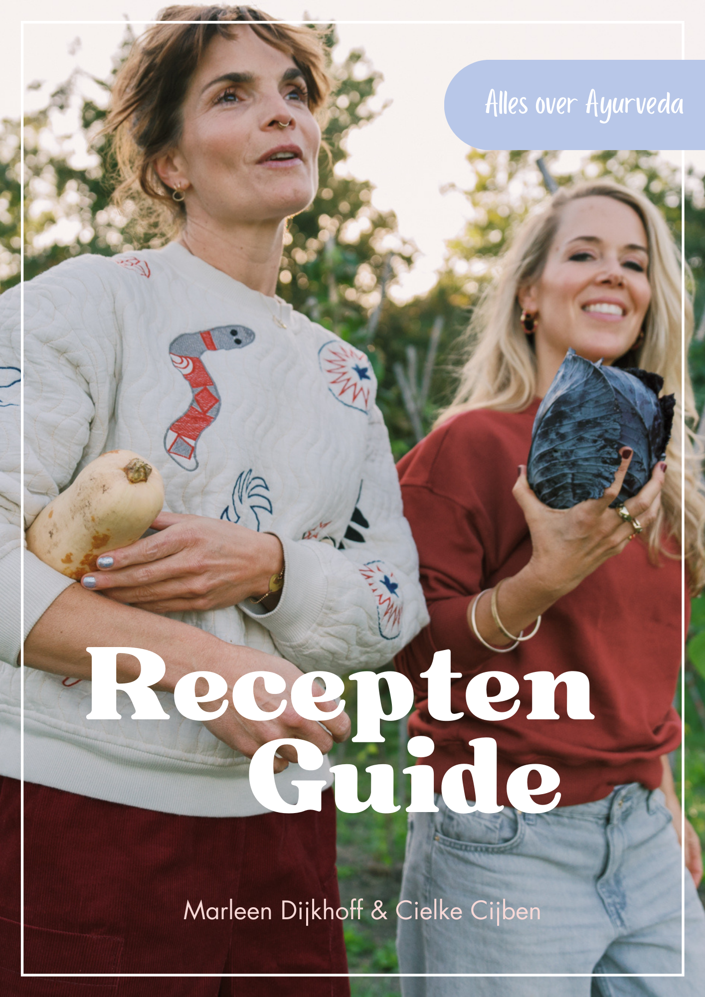 Two women outdoors, one holding a large parsnip and the other holding a head of purple cabbage, with greenery in the background. The cover features a light border, a blue speech bubble that says 'Alles over Ayurveda,' and large white text that reads