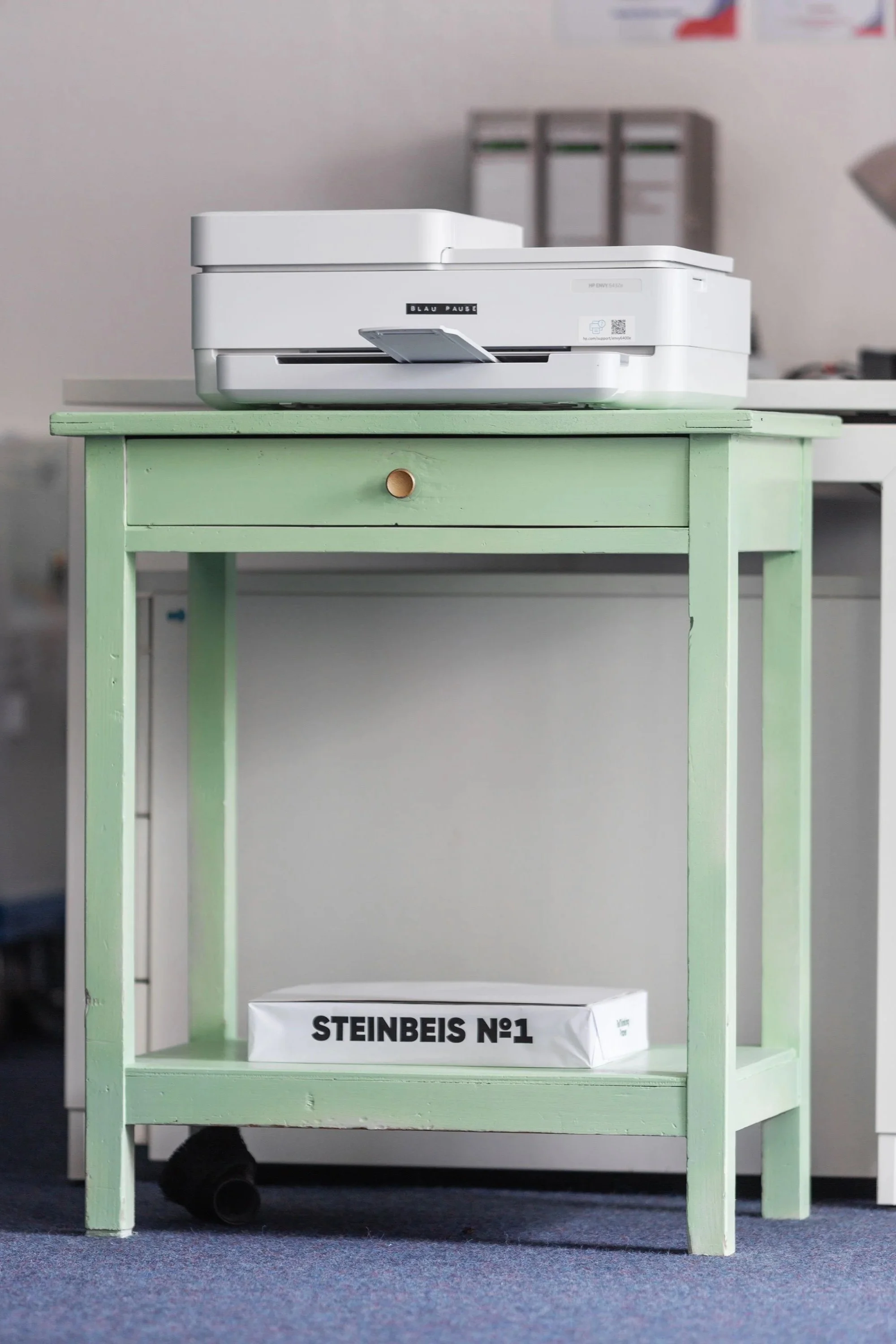 Das Bild zeigt einen grünen Tisch mit einem Drucker.