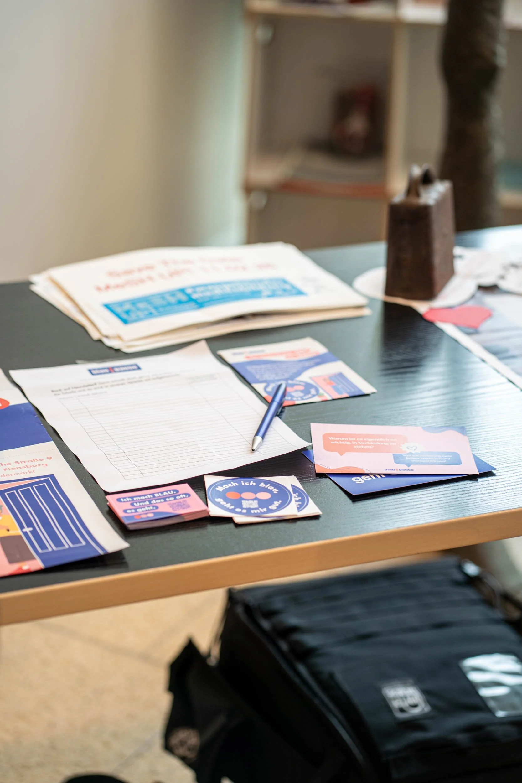 Auf dem Bild sind Flyer und Sticker von der blau:pause auf einem Tisch zu sehen.