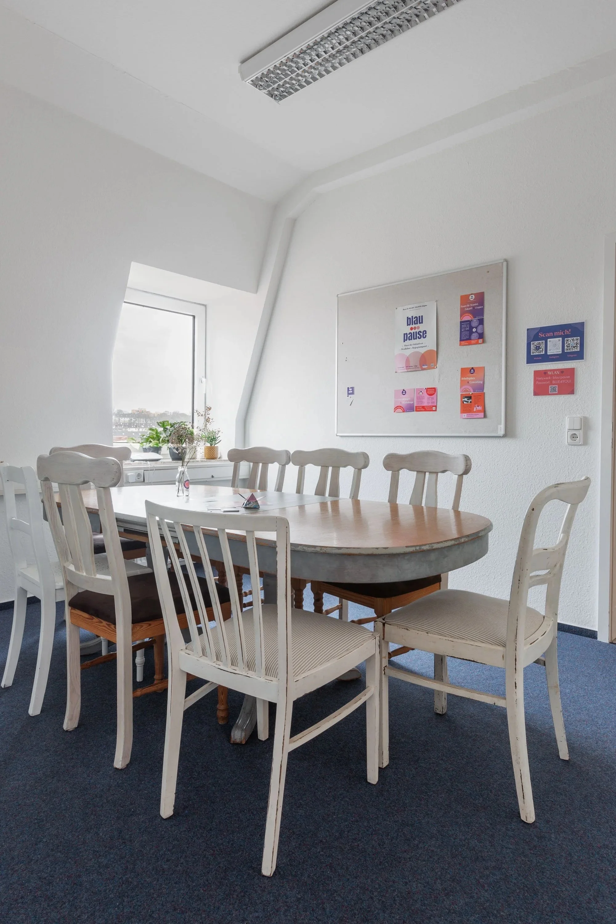 Auf dem Bild sieht man die kleine:pause. Eine kleines Besprechungsraum mit einem Tisch und 7 weißen Holzstühlen.