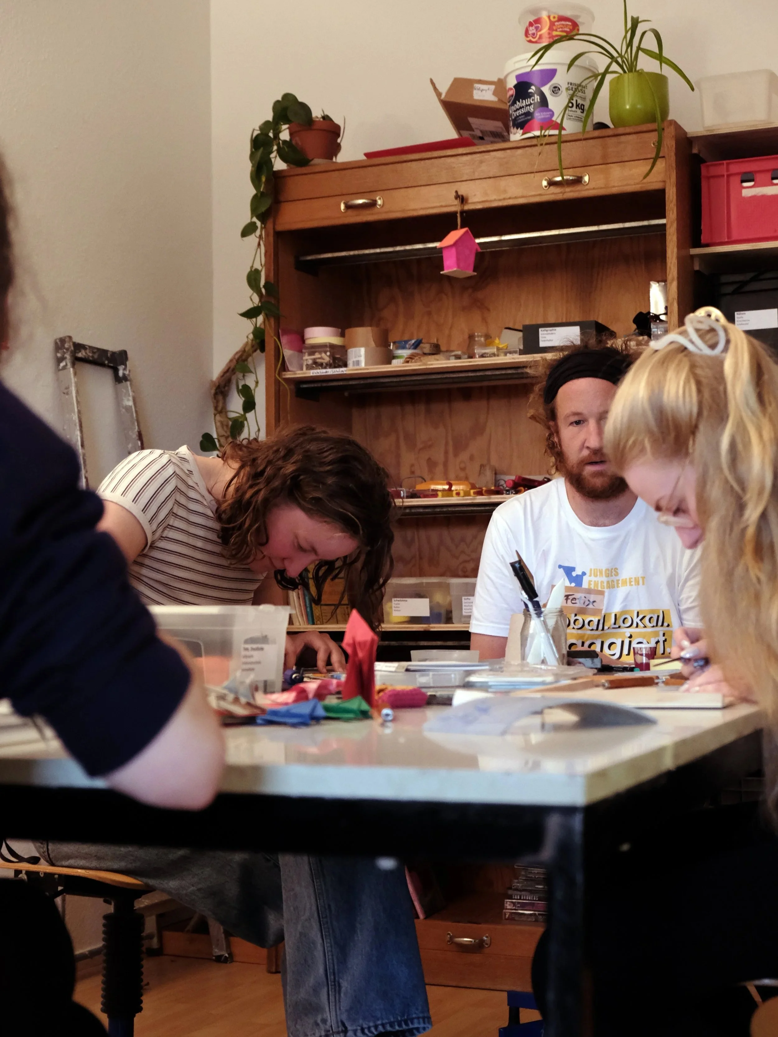 Mehrere Personen sitzen an einem Tisch und basteln.