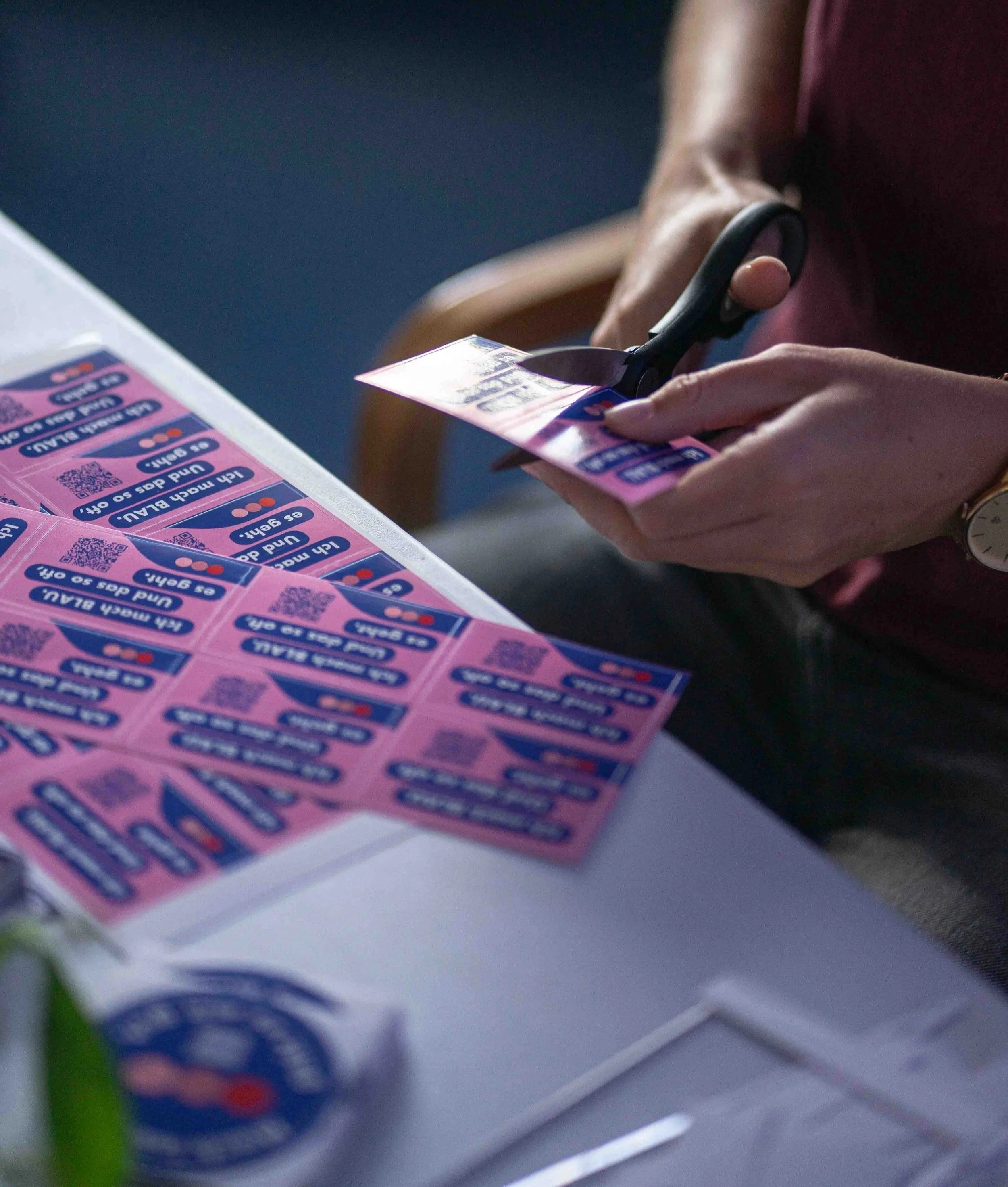 Das Bild zeigt eine Nahaufnahme auf eine Hand, die Sticker durchschneidet.