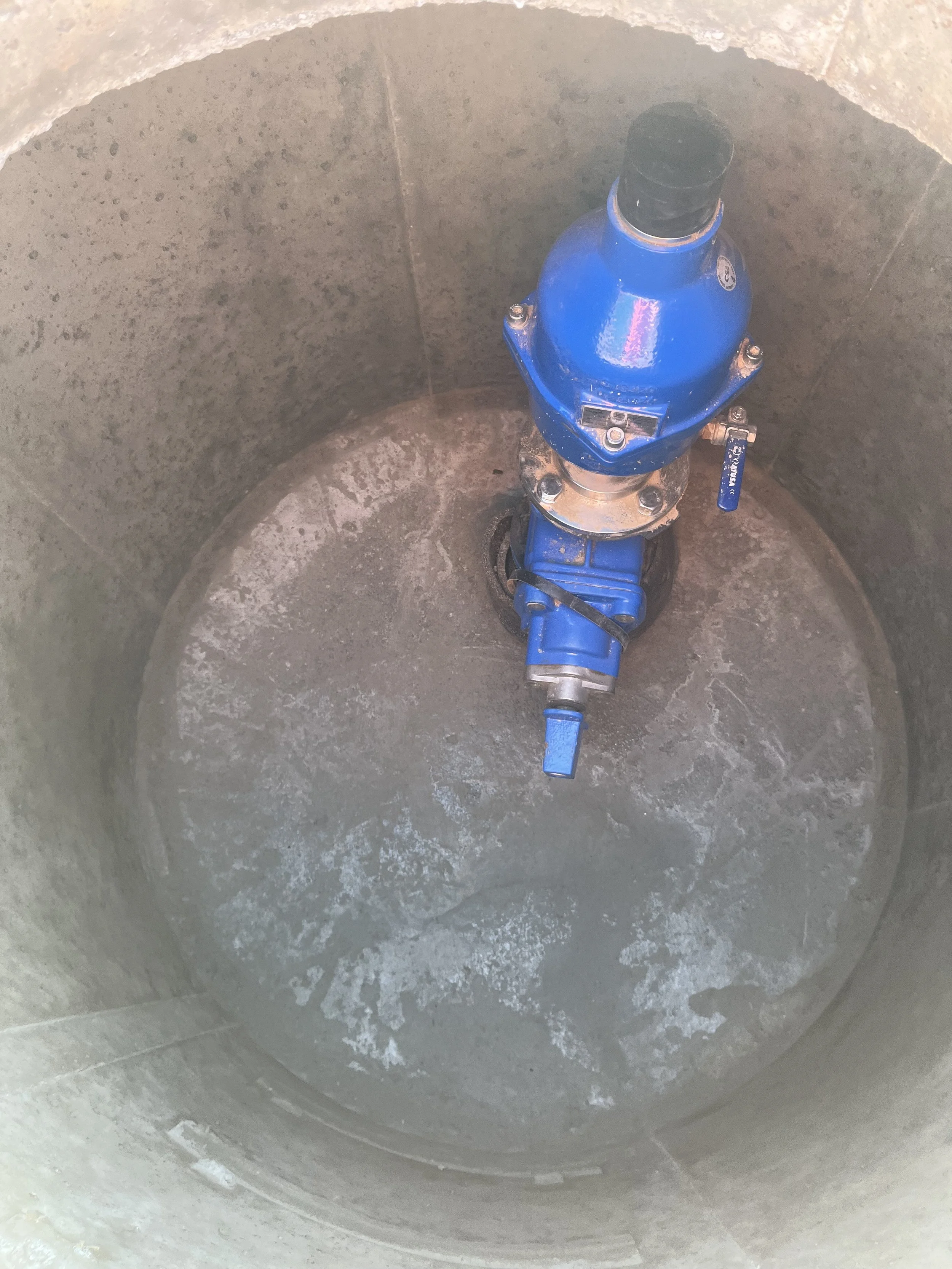 Blue fire hydrant inside a concrete circular chamber.