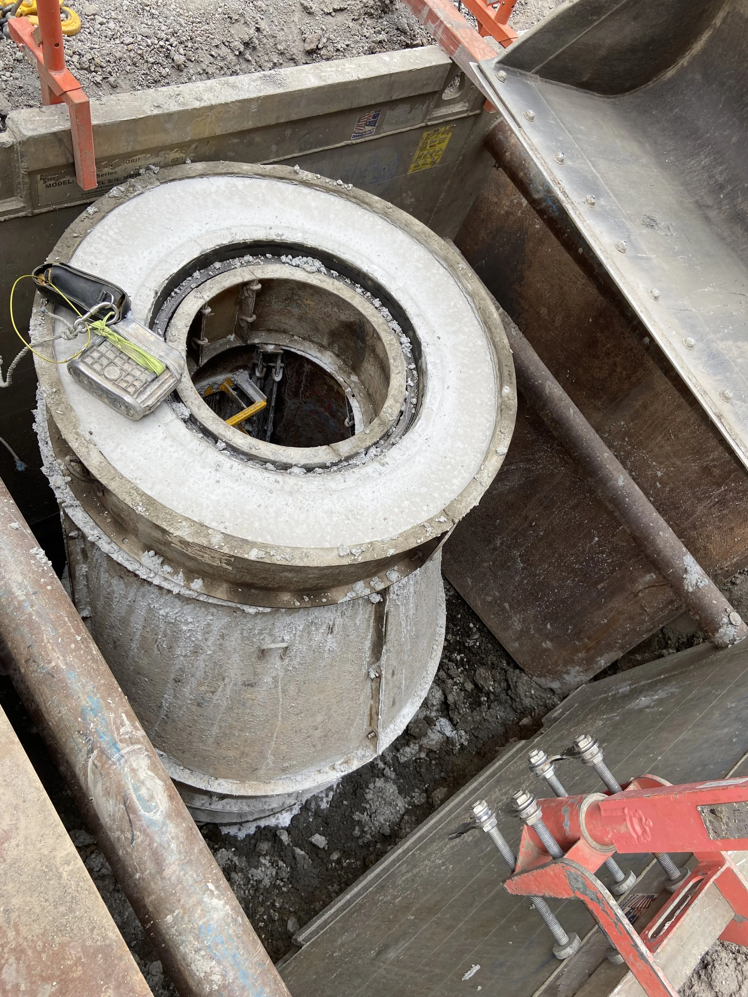 Close-up of a large, circular underground concrete structure or vault, possibly part of a utility or sewer system, with construction tools and equipment around it.