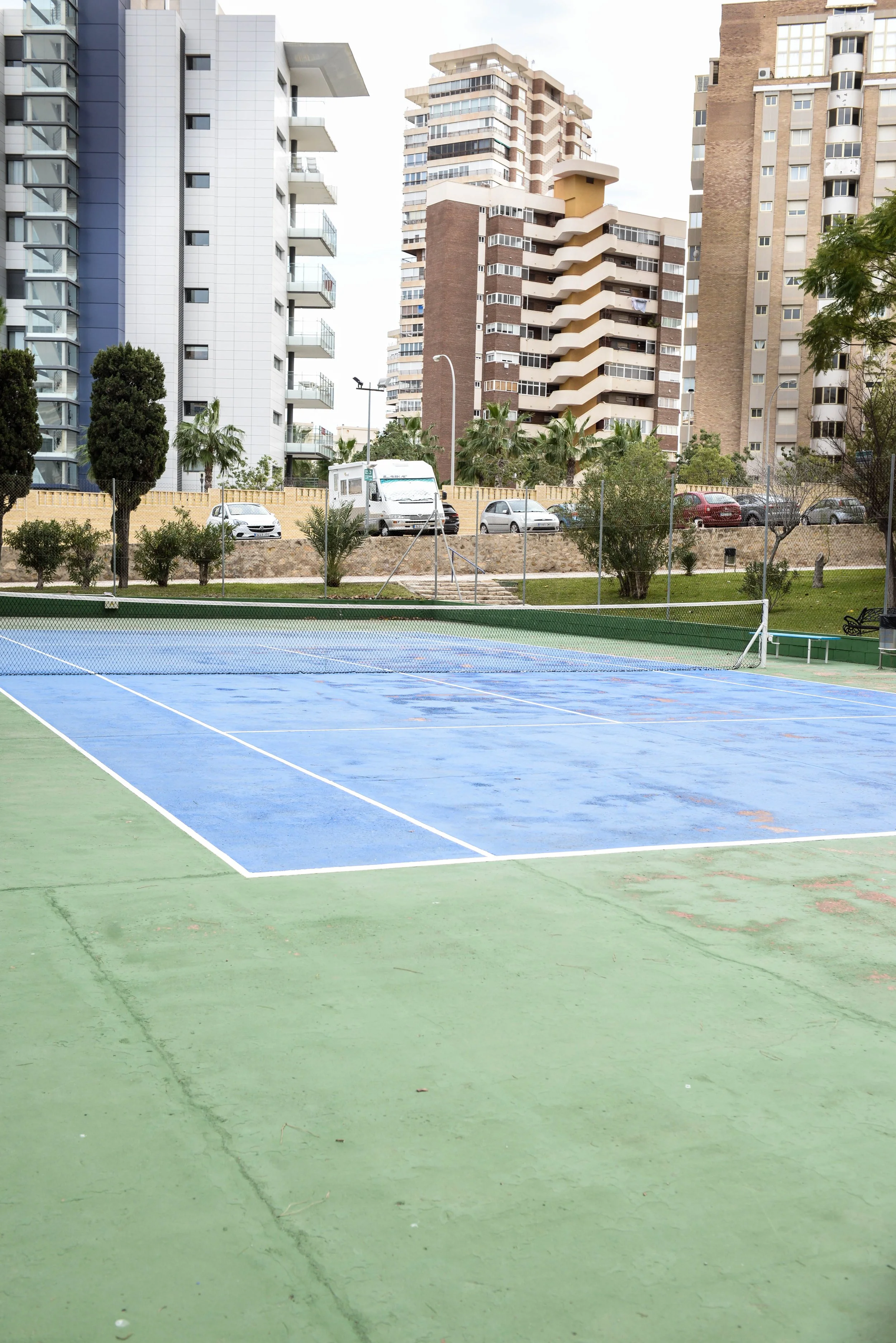Un court de tennis en extérieur avec des immeubles résidentiels en arrière-plan.