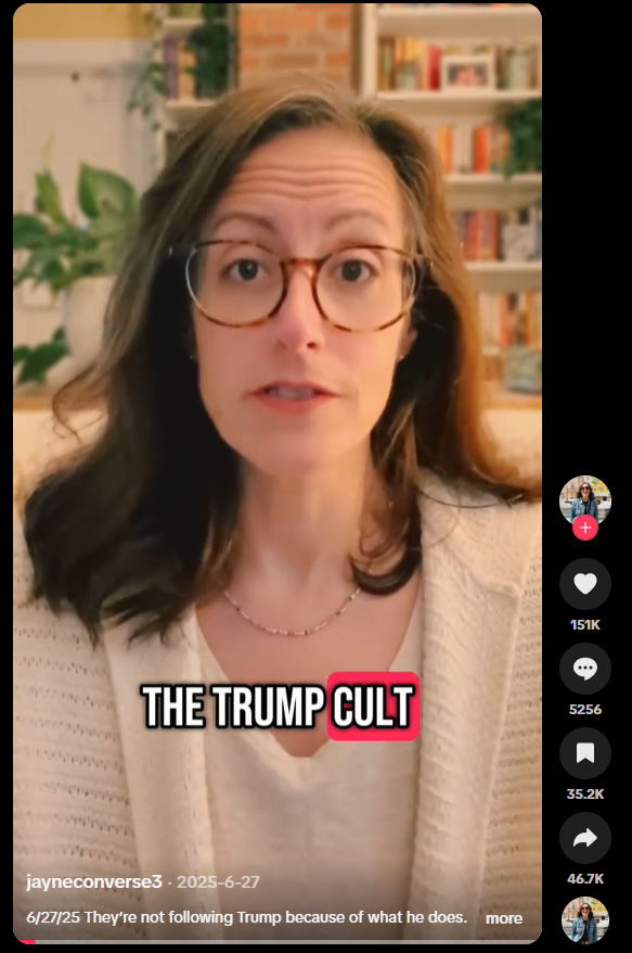 A woman with glasses and brown hair, speaking in a room with a bookshelf and plants in the background. Text overlay: "THE TRUMP CULT."