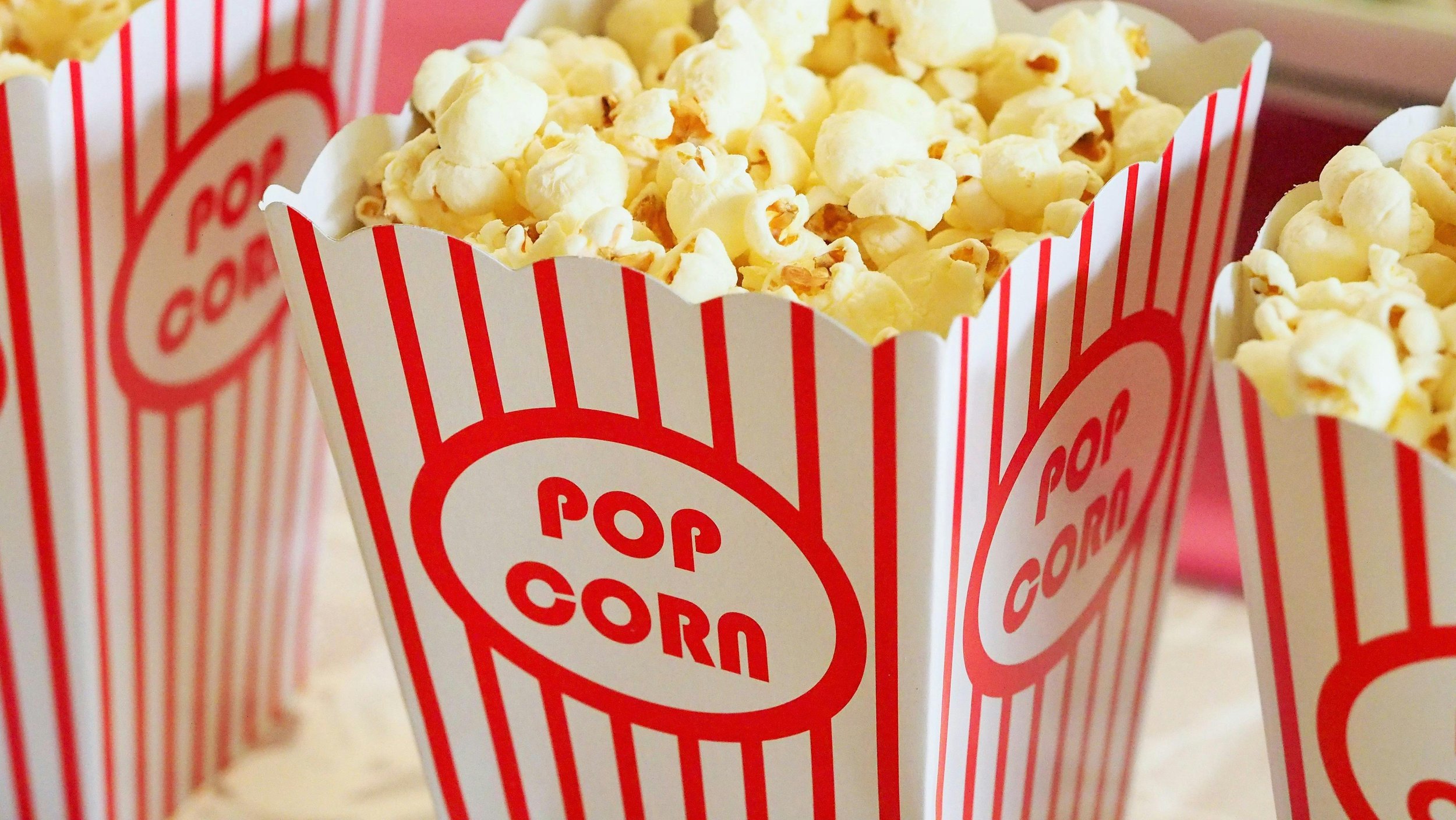 Red and white striped popcorn container filled with popcorn.