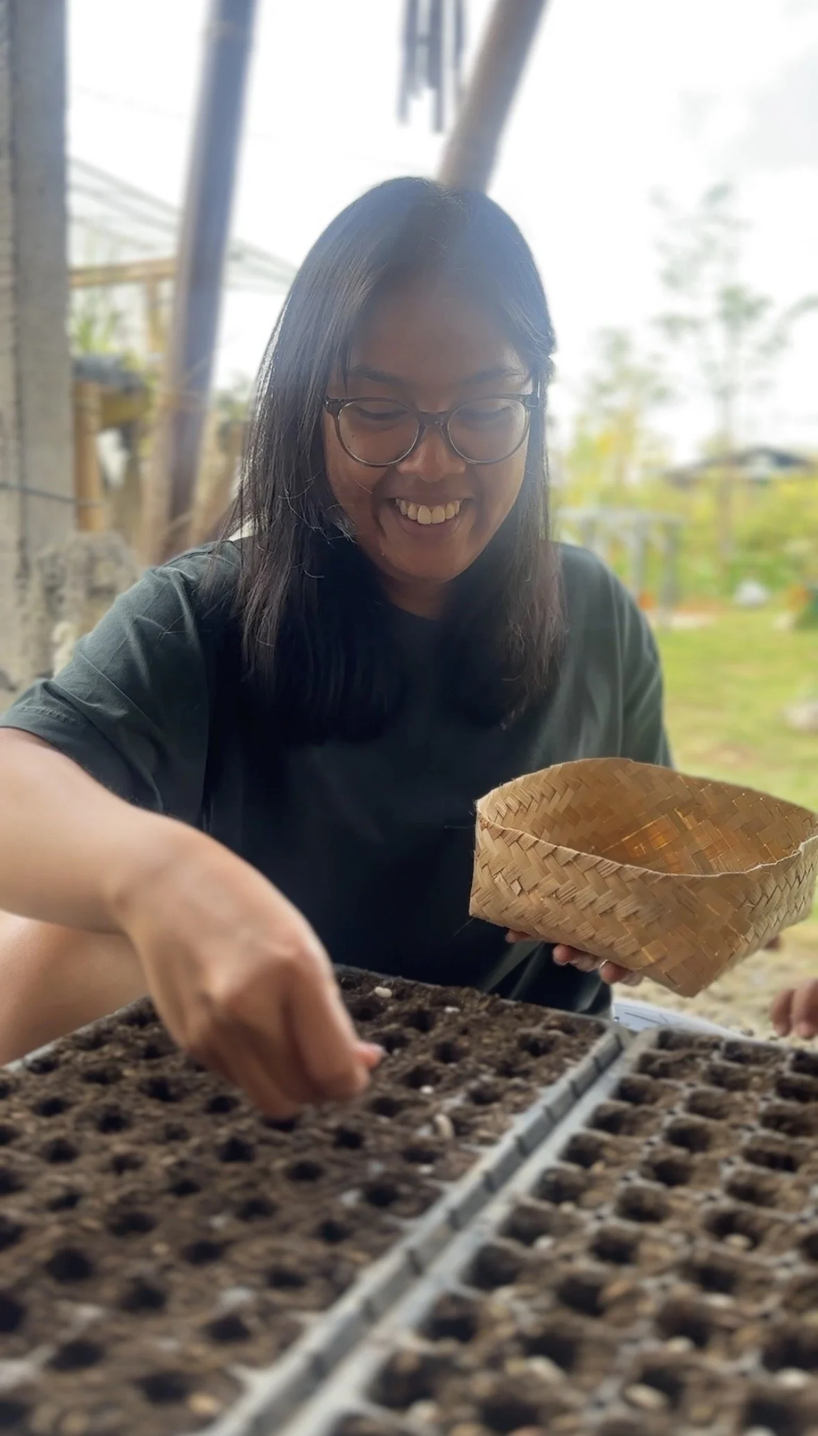 Smiling woman planting seedlings in soil at outdoor garden or farm
