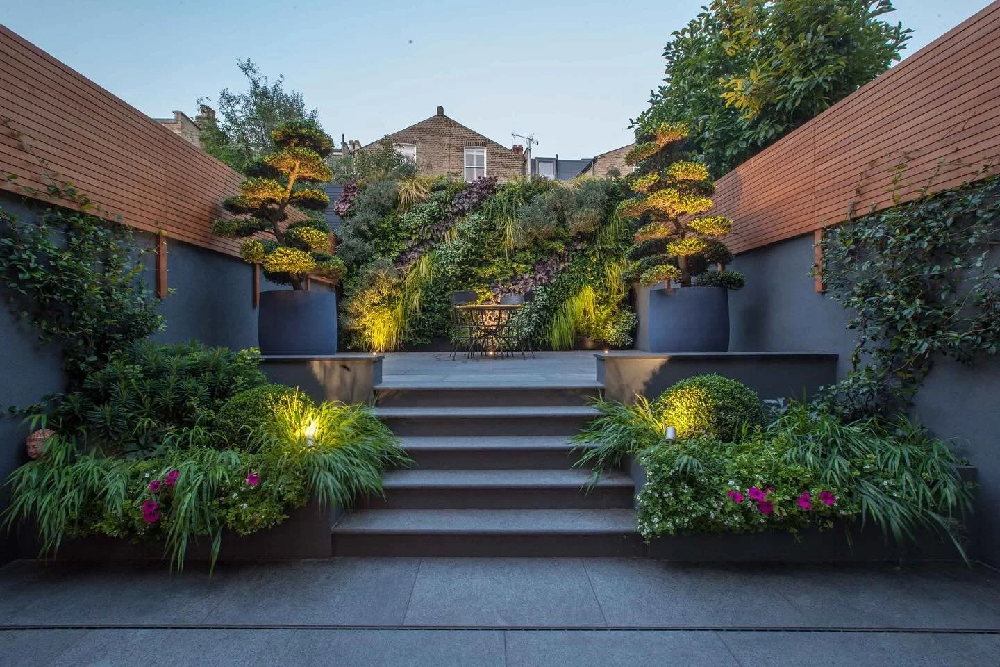 This wonderful photo was taken by @simonorchardgardens of the lovely rear garden he designed and we detailed and coordinated in Clapham. The dark grey walls look dramatic in the fading light and the greenery stands out against them. The amazing real 