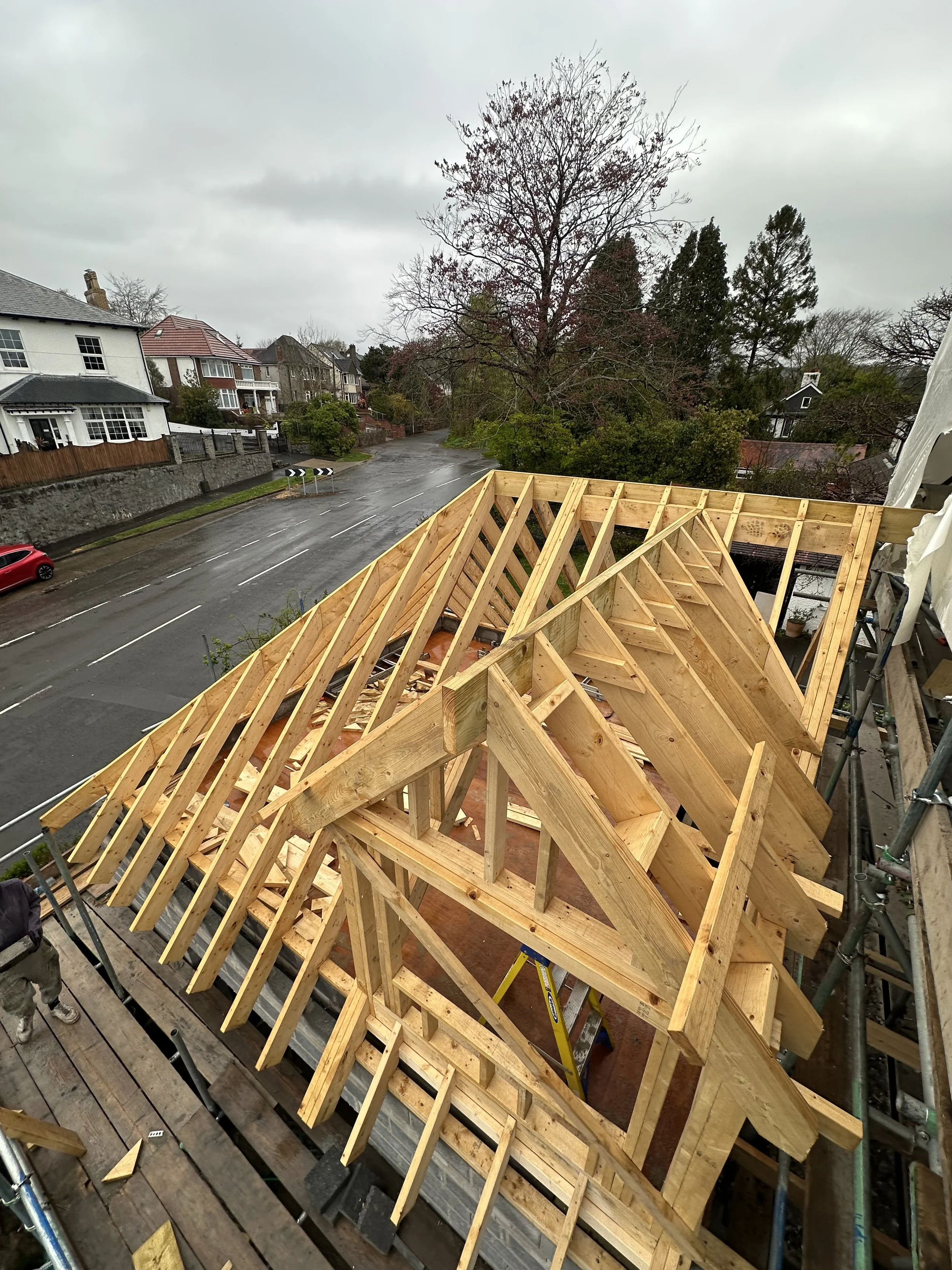 Timber frame roof structure under construction with exposed trusses and beams