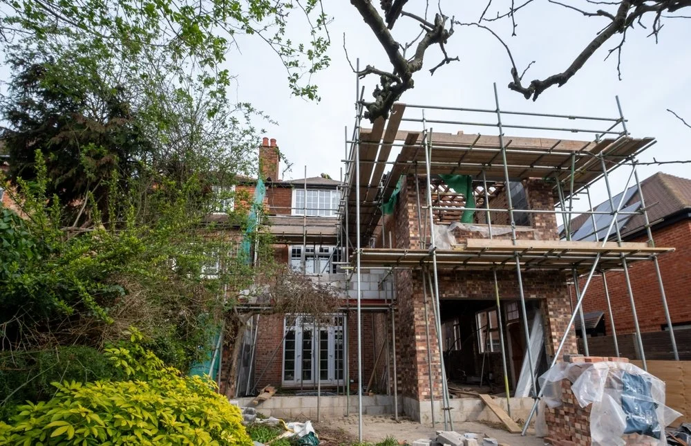 Double-storey house extension under construction with scaffolding and timber structure