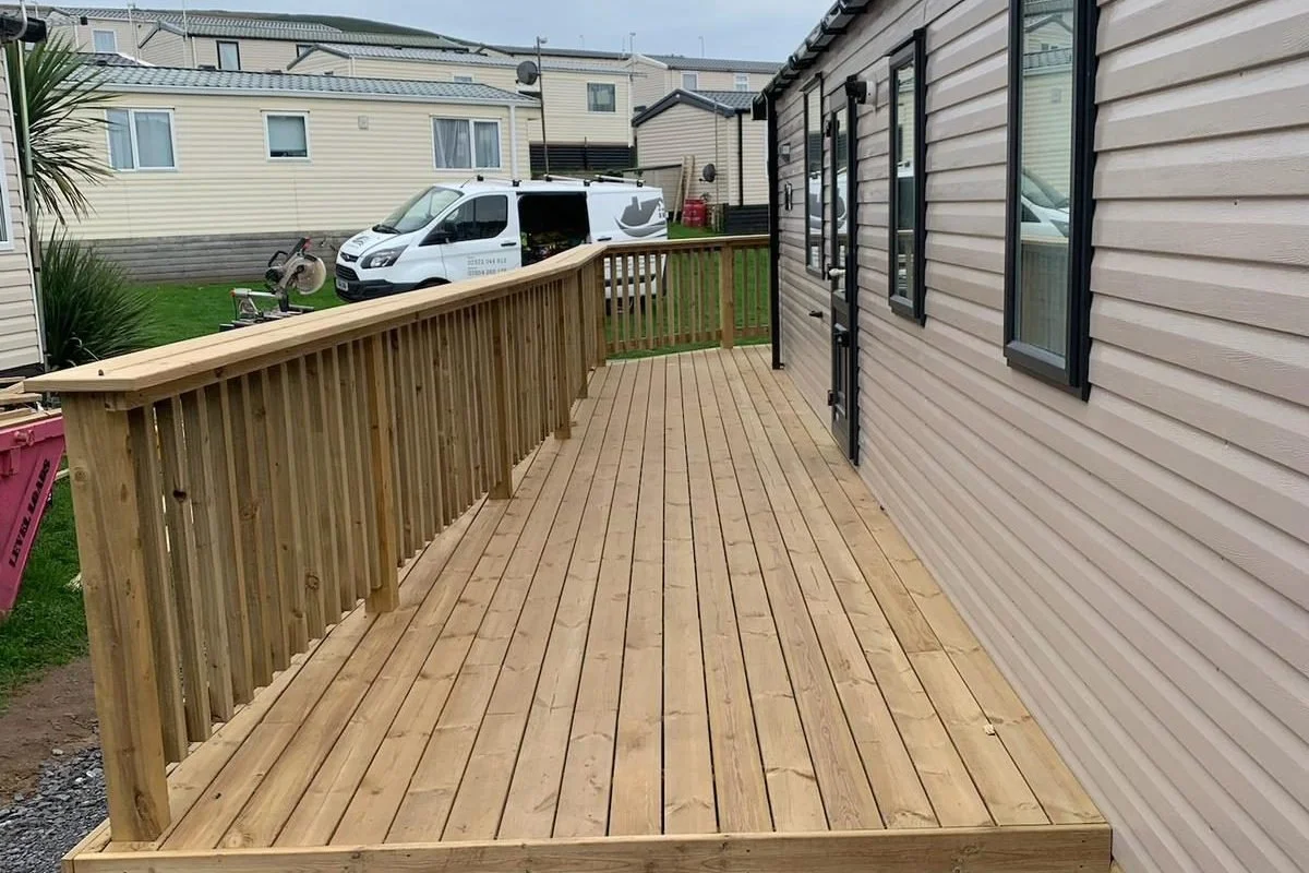 Timber decking installation alongside a caravan with balustrade and walkway