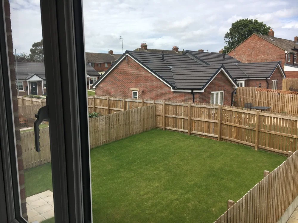 Garden fencing installation with timber panels enclosing residential lawn