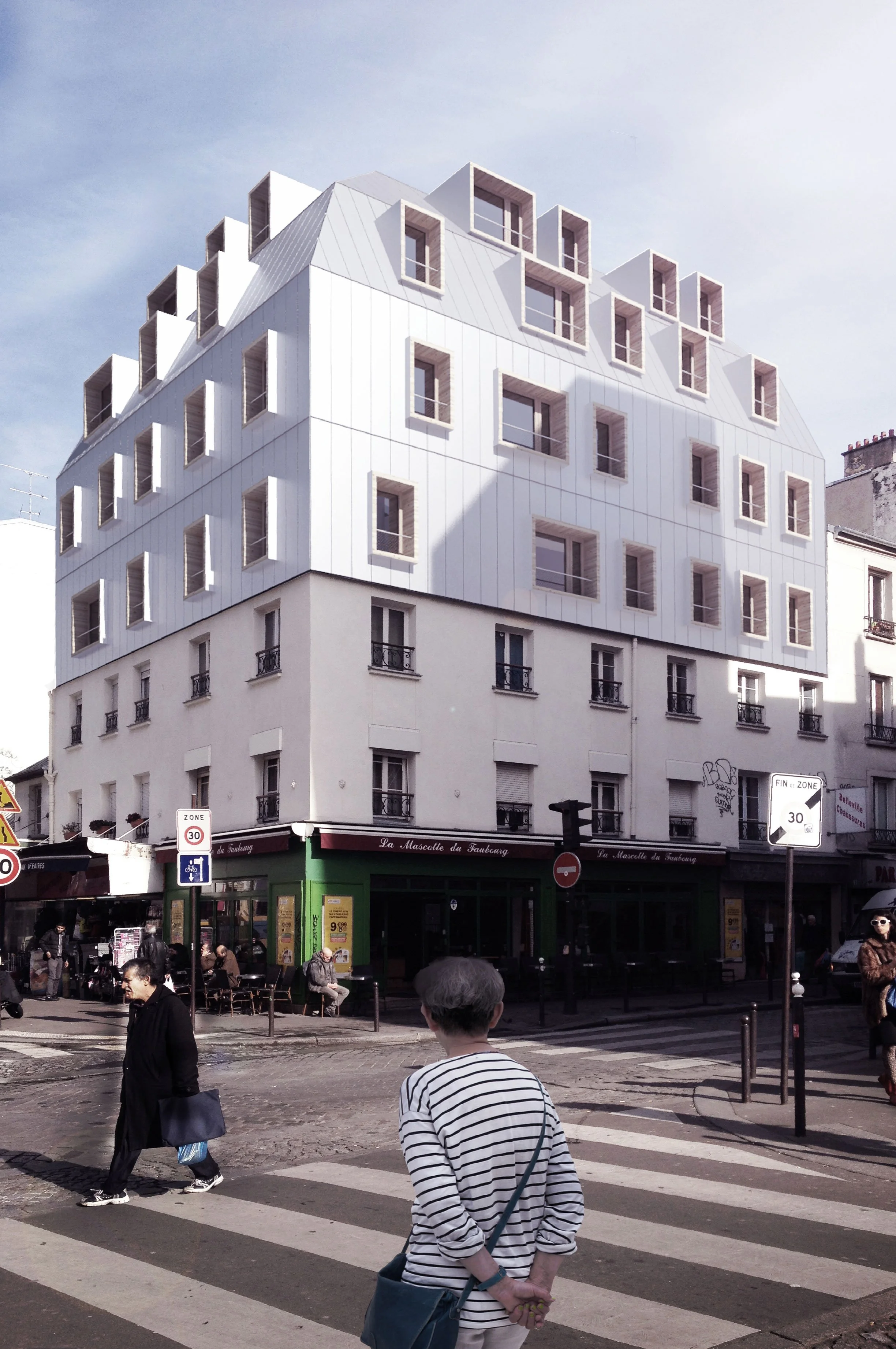 Une vue urbaine avec un bâtiment moderne blanc à plusieurs étages et un rez-de-chaussée coloré en vert. En premier plan, des piétons traversent une zone piétonne avec des passages pour piétons. Certaines personnes portent des sacs et des vêtements dé