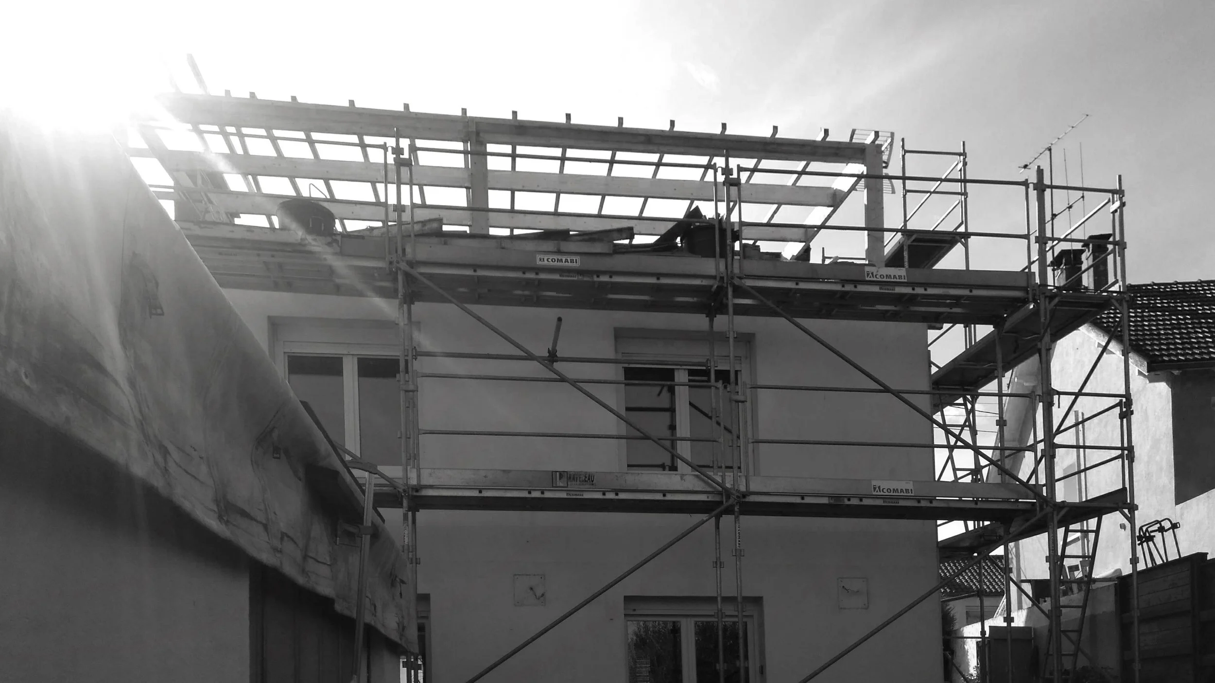 Échafaudages en construction de bâtiment avec un ciel en arrière-plan, en noir et blanc.
