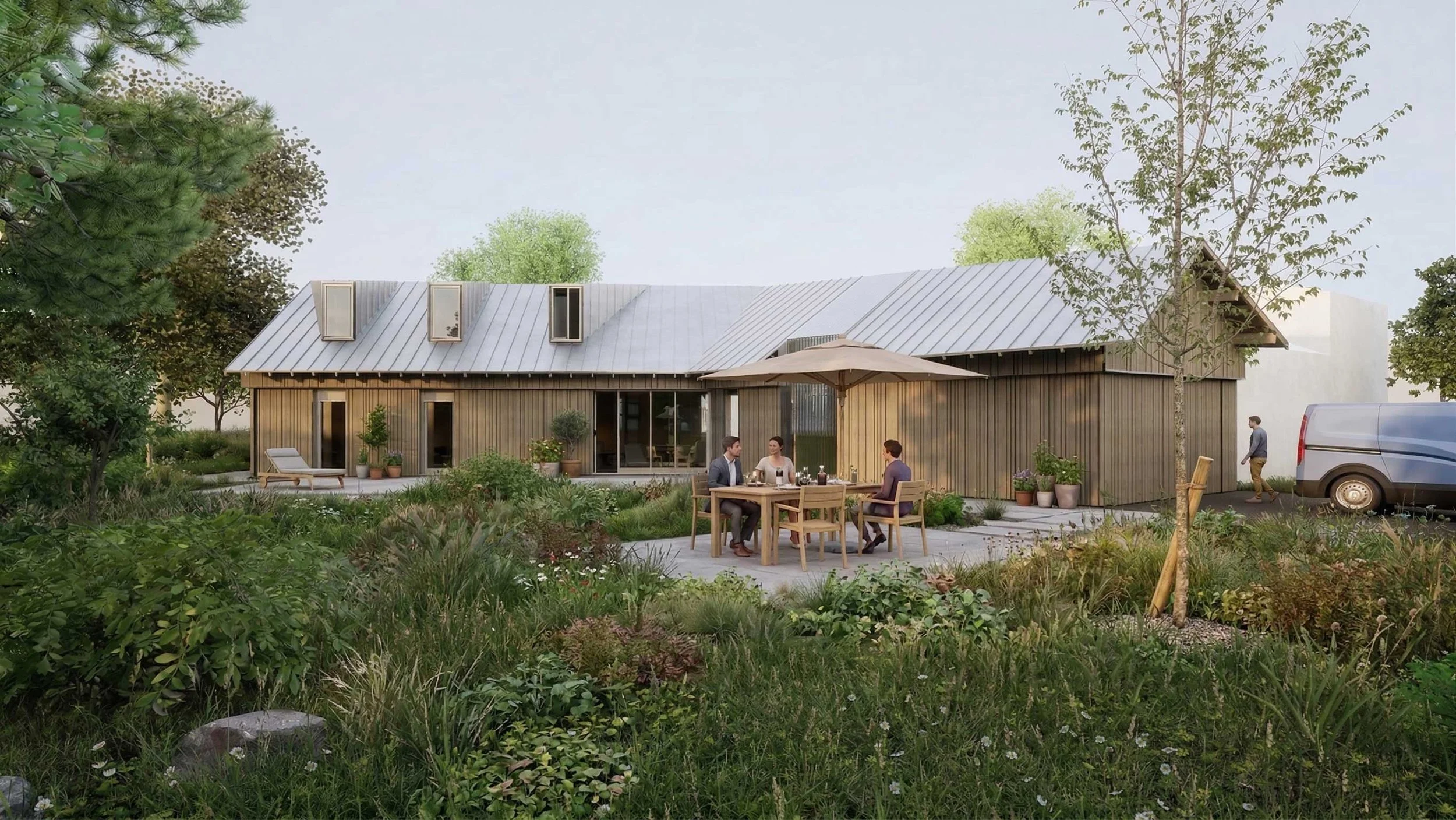 Une maison moderne en bois avec un toit en métal, entourée de jardin avec des arbustes et des arbres, où trois personnes sont assises autour d'une table à l'extérieur, profitant d'un repas, tandis qu'une autre personne marche près d'un véhicule utili