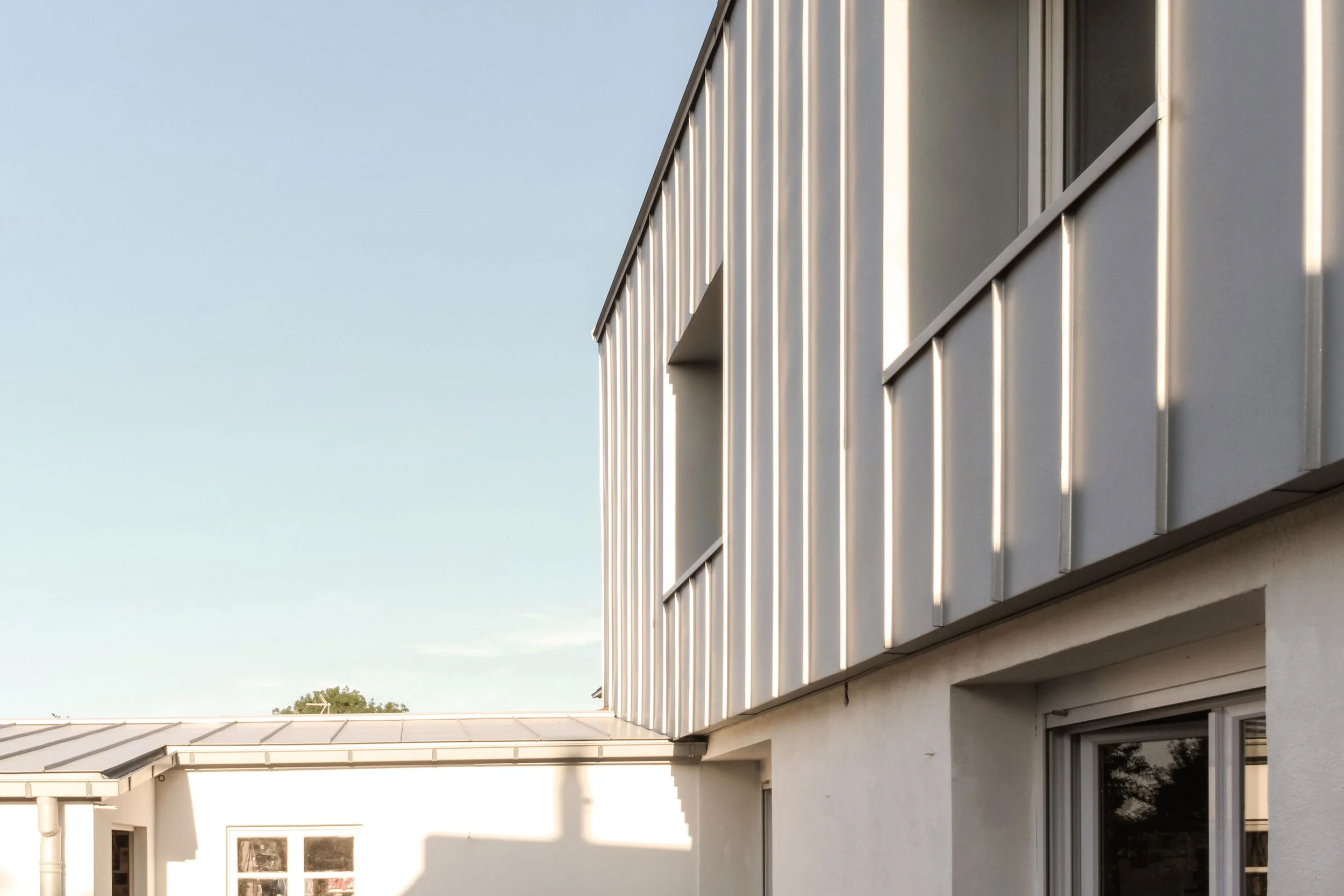 Vue d'un bâtiment résidentiel moderne avec des volets en aluminium, sous un ciel dégagé.