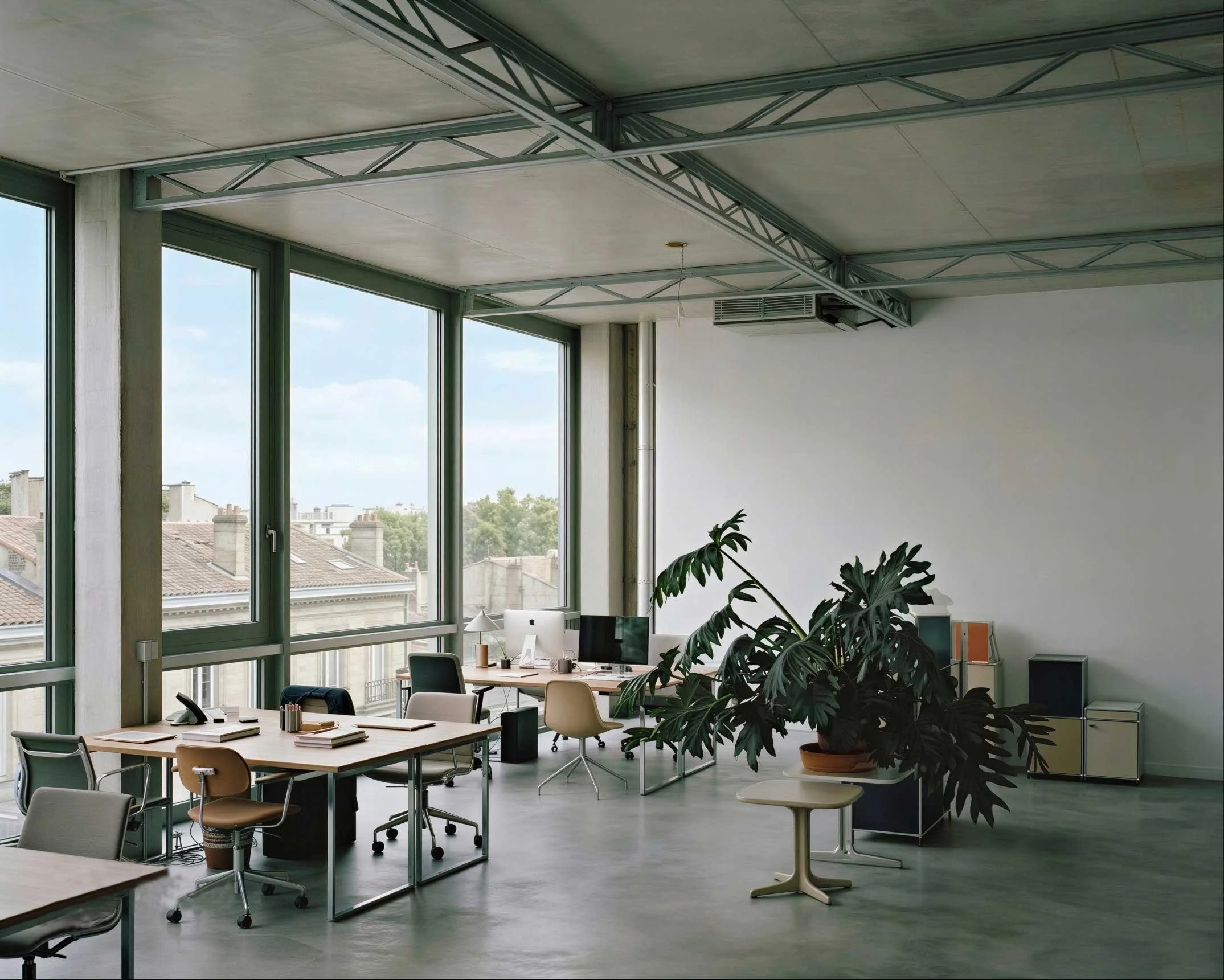 Espace de bureau moderne avec grandes fenêtres laissant entrer la lumière naturelle, plusieurs bureaux avec chaises et ordinateur, plantes vertes, et plafond en béton avec structures métalliques
