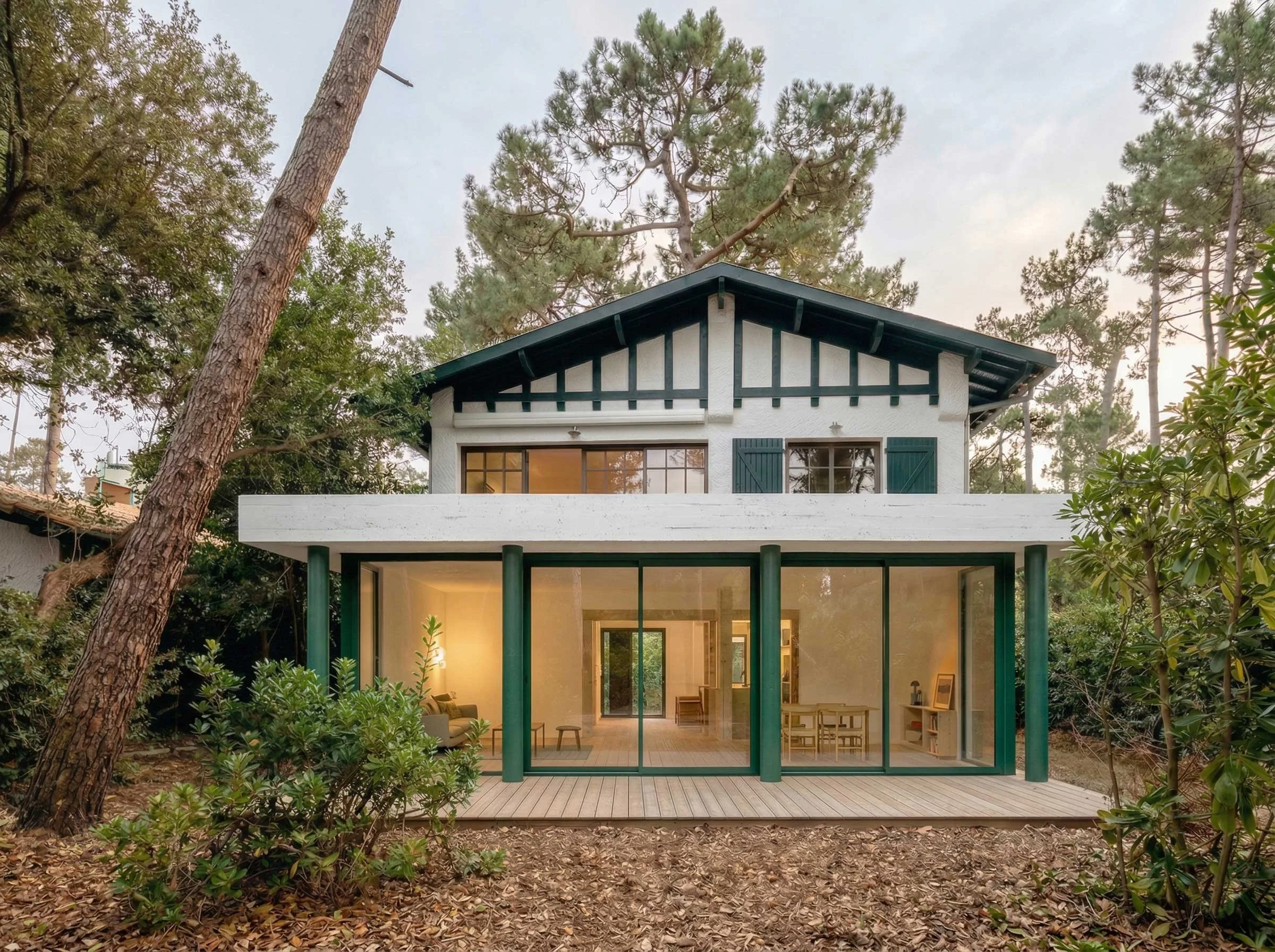 Une maison moderne avec de grandes fenêtres en verre, entourée d'arbres et de végétation, vue extérieure en soirée