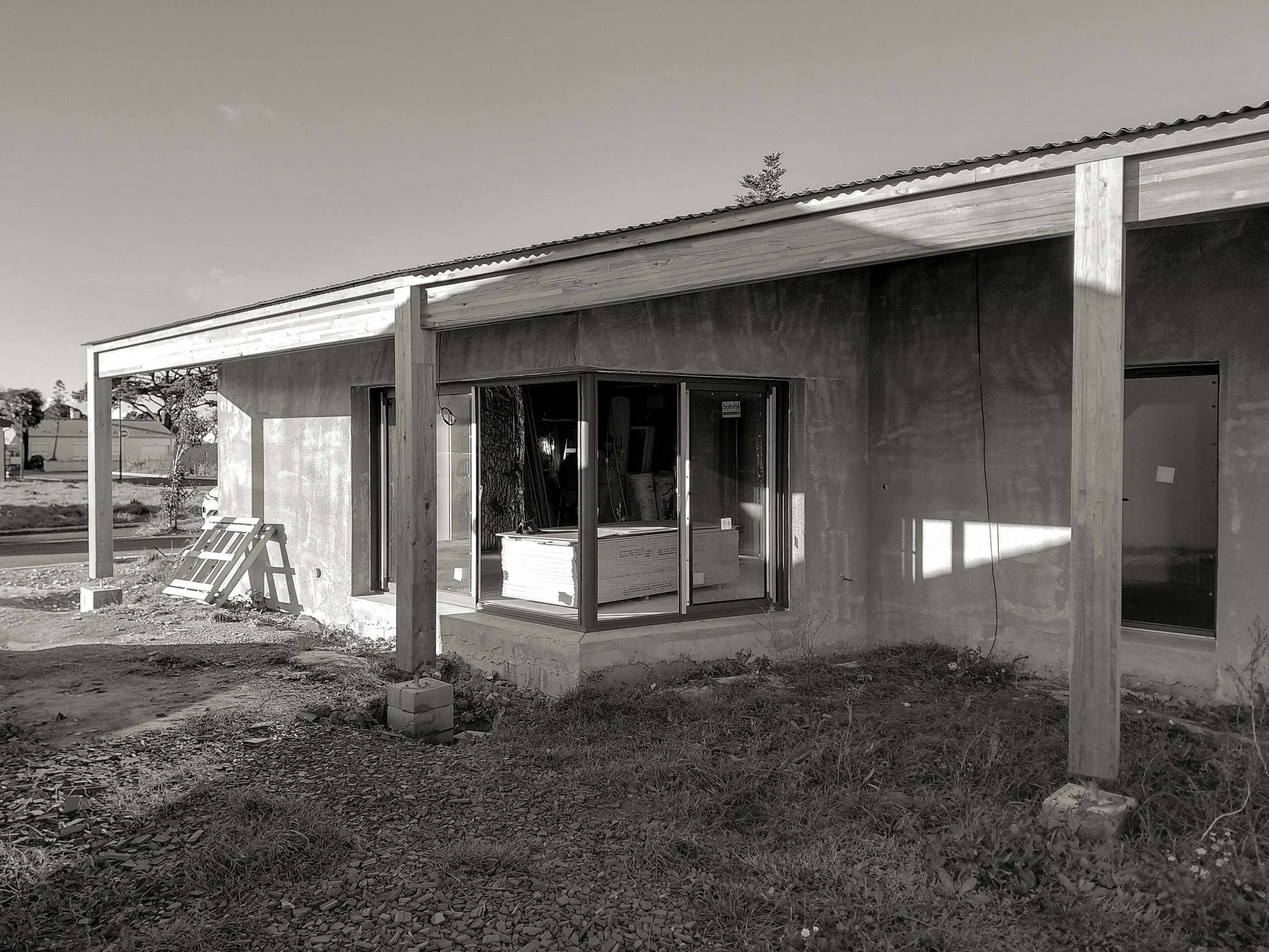 Construction d'une maison avec structure en bois et fenêtres installées, chantier en cours avec outils et matériaux