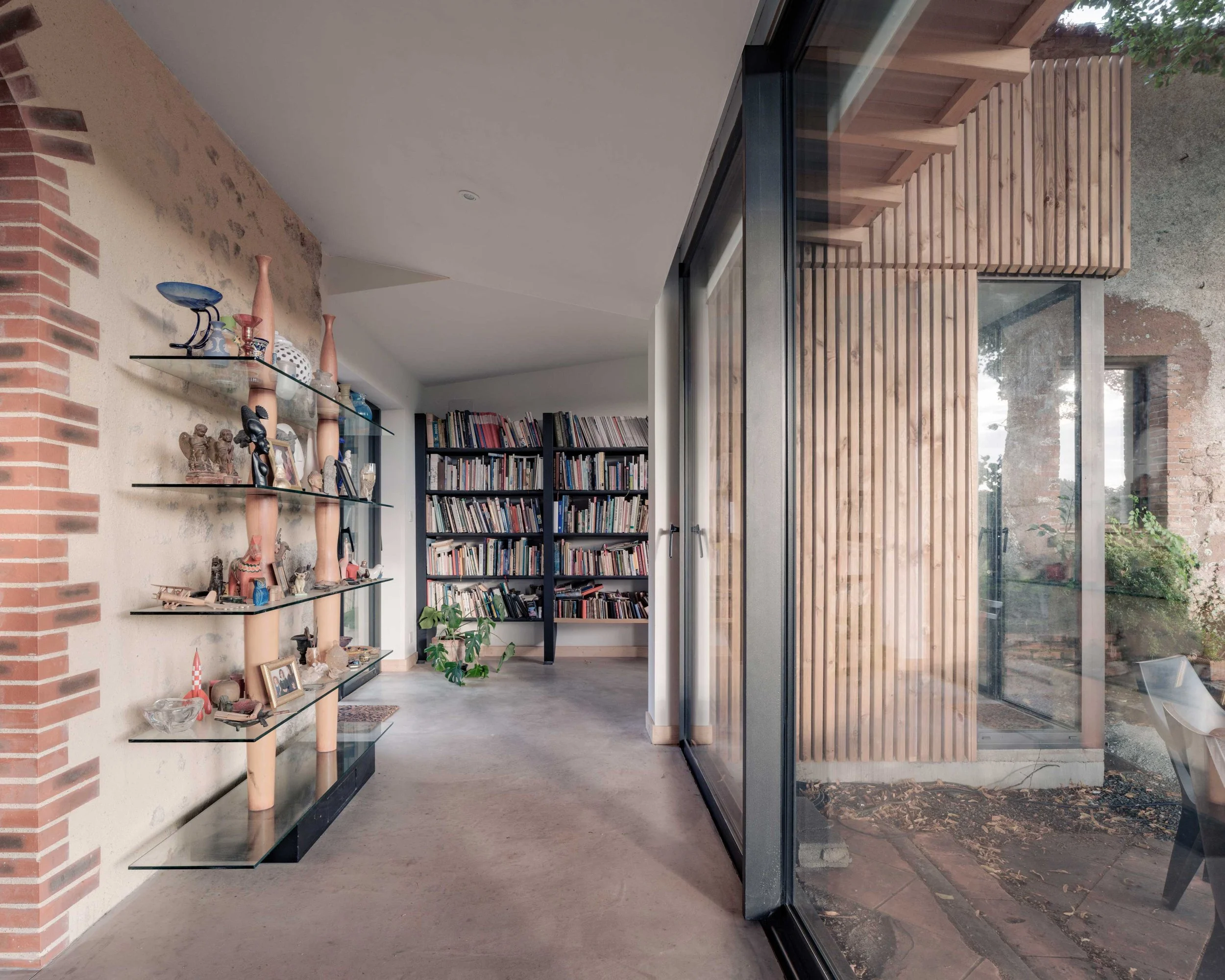 Intérieur moderne avec étagères en verre, objets décoratifs, et bibliothèque.
