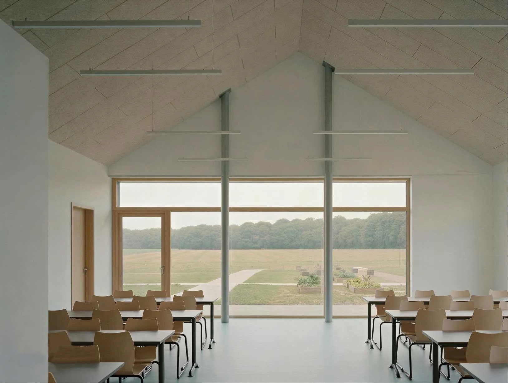 Salle de classe vide avec grandes fenêtres donnant sur un paysage rural