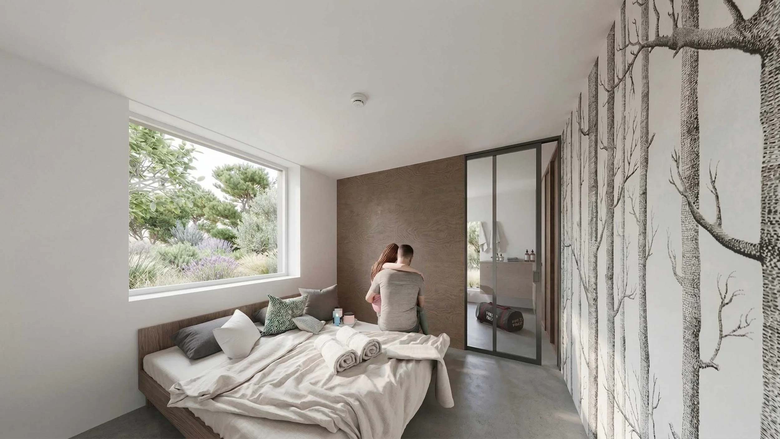 Une chambre avec un lit fait, des coussins, un grand panneau en bois, une fenêtre laissant entrer la lumière naturelle, une vue sur la végétation extérieure, et deux personnes assises sur le lit. Mur décoratif avec un motif d'arbres en noir et blanc.