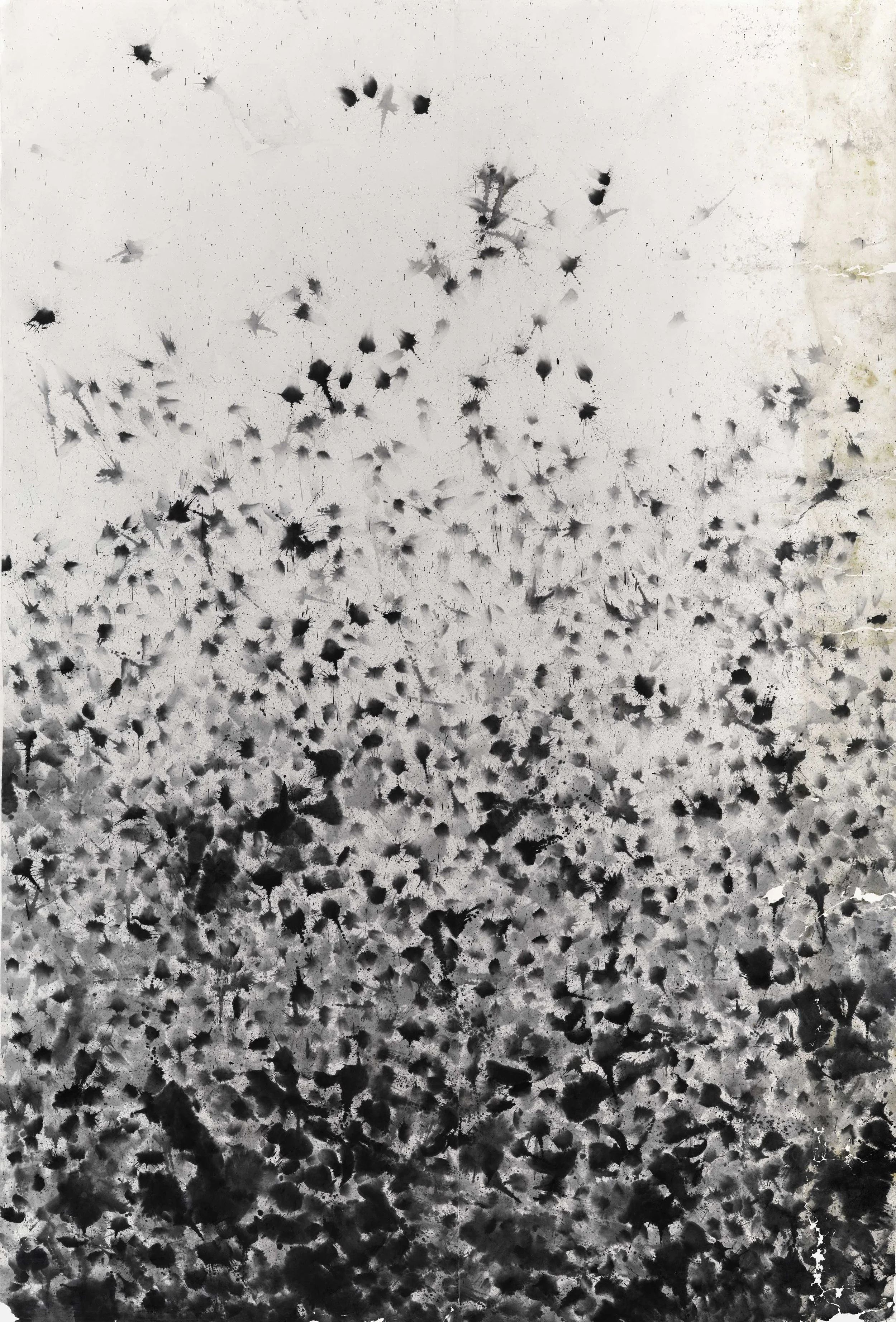 Black spray paint splatters on a white wall creating an abstract pattern.